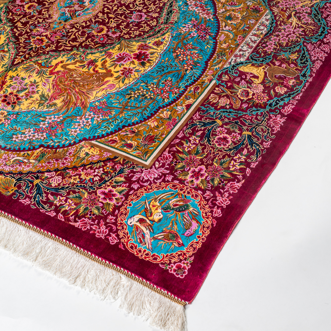 Opulent silk rug with ruby base and turquoise floral accents. Detailed handwoven artistry ideal for luxury, dramatic interior settings.