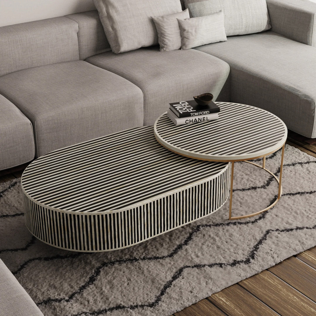 Black bone inlay nesting coffee table with vertical striped pattern and gold base, styled in a modern living room.