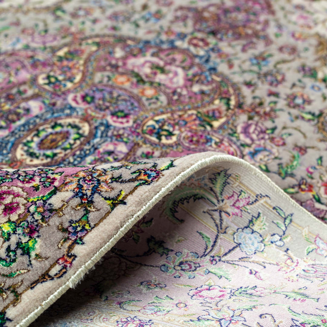 The Savina silk rug features a pink and beige floral medallion design, handwoven in fine silk with intricate detailing.