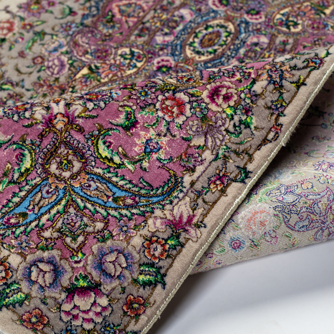 The Savina silk rug features a pink and beige floral medallion design, handwoven in fine silk with intricate detailing.