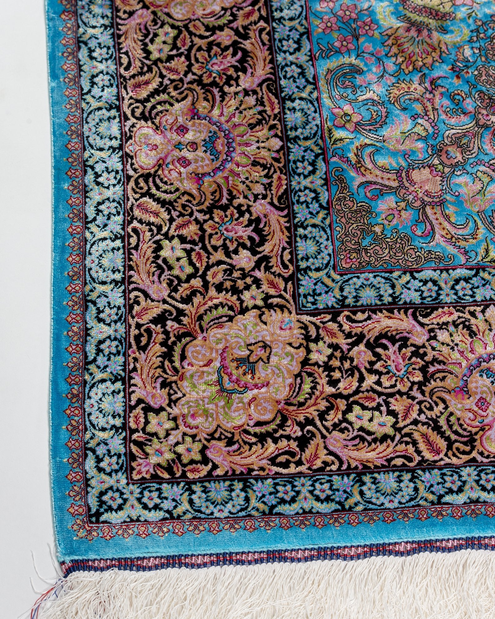 angled view with a fringed end on the Serena turquoise silk rug