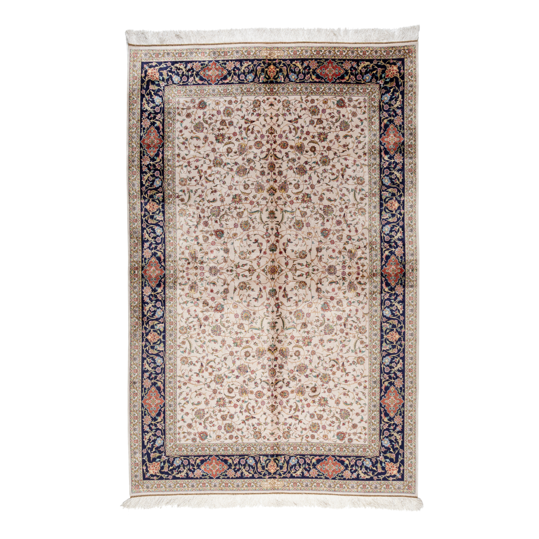 Ivory silk rug with intricate floral patterns in navy, rose, gold, and turquoise, framed with an ornate navy border.