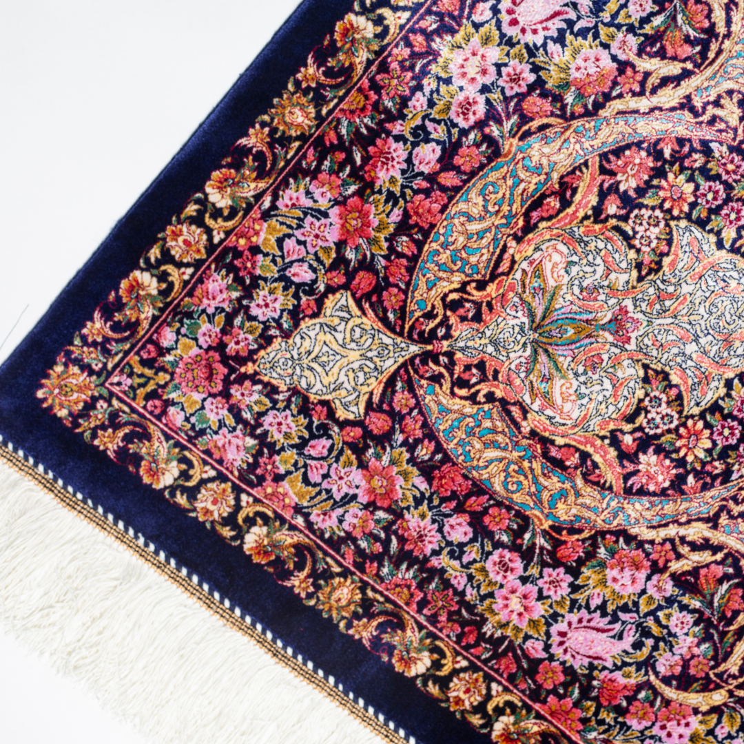 Elegant silk rug in navy, pink, gold, and turquoise with detailed Persian-inspired floral and dancer motifs.