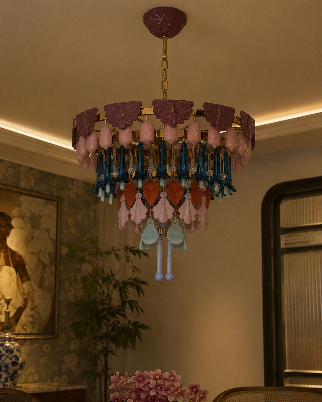 The Canopy Chandelier by The Qratist features handcrafted porcelain petals and coloured glass accents suspended from a gold plated frame, creating a layered botanical statement inspired by a flourishing garden canopy.