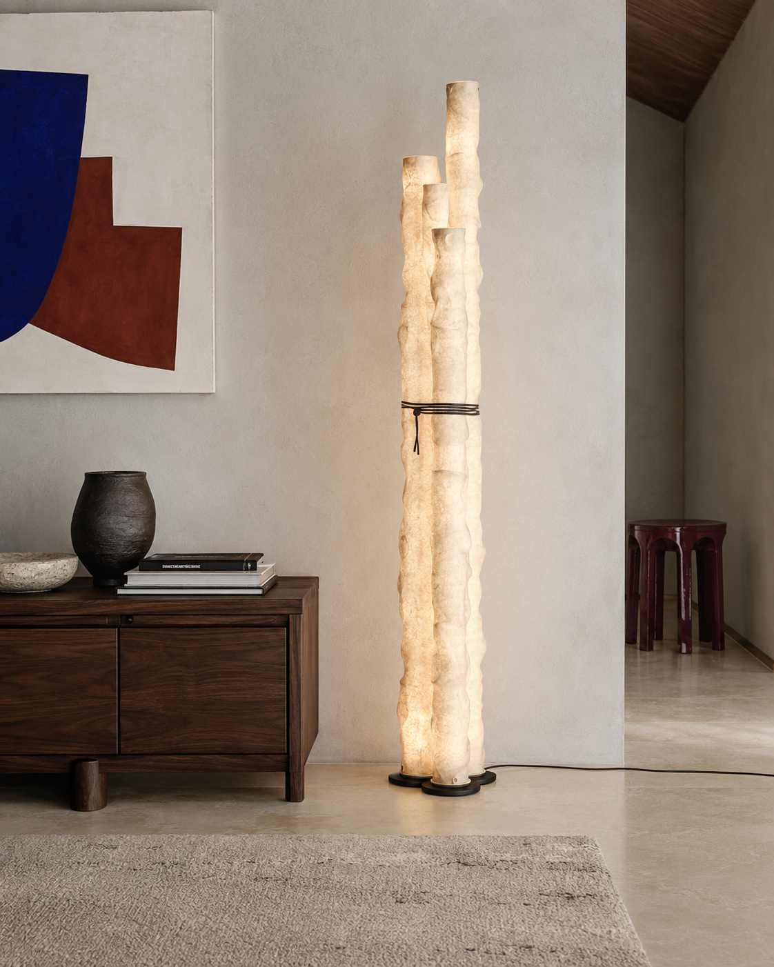 The Frosted Floor Lamp by The Qratist features handcrafted textured paper tube columns secured with a minimalist grey metal frame, creating a sculptural contemporary floor lighting statement with a warm ambient glow.