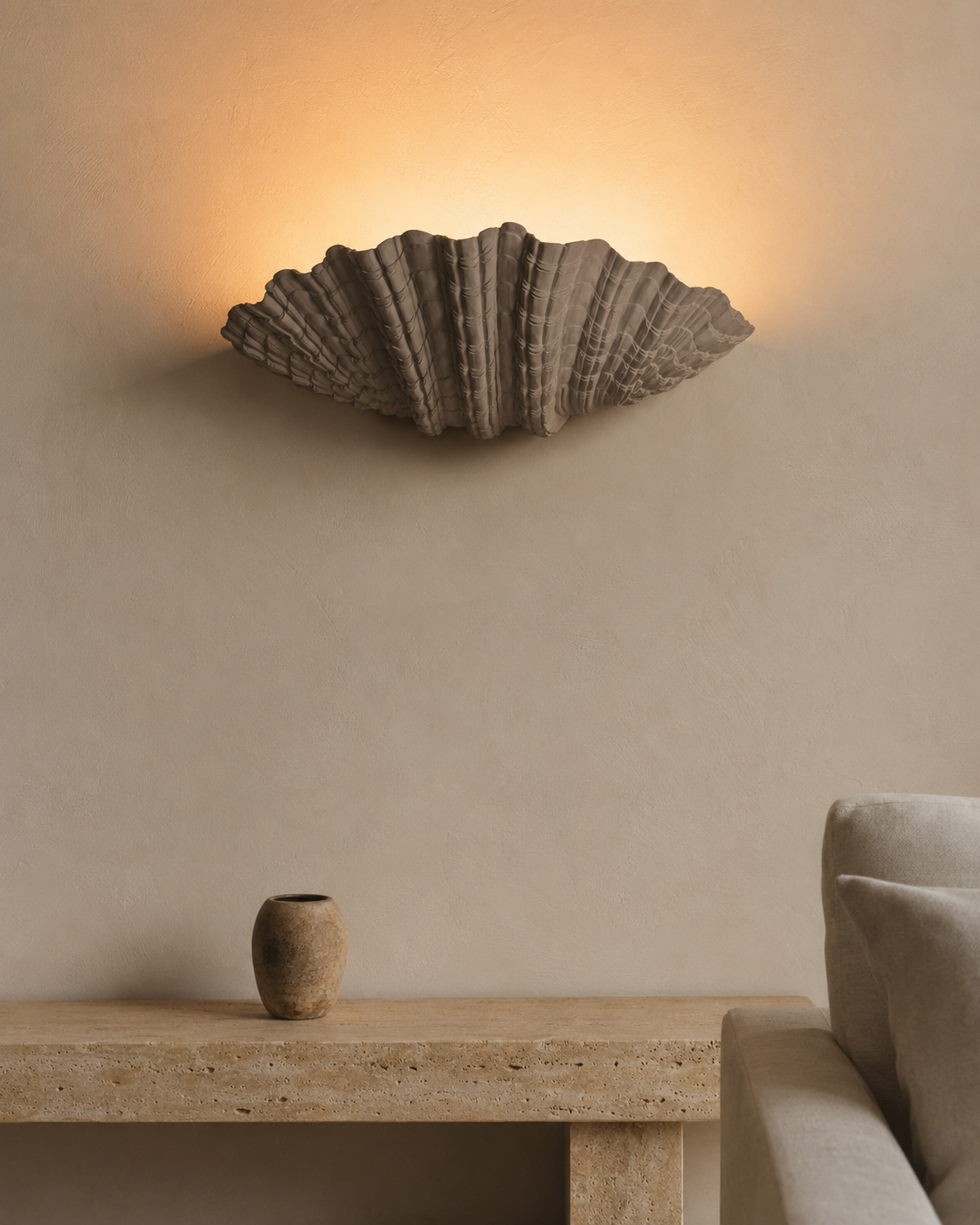 The Grotto Wall Light by The Qratist features a handcrafted sculptural form inspired by coastal grottos, crafted from plaster, polyresin, and sandstone to create warm ambient illumination.