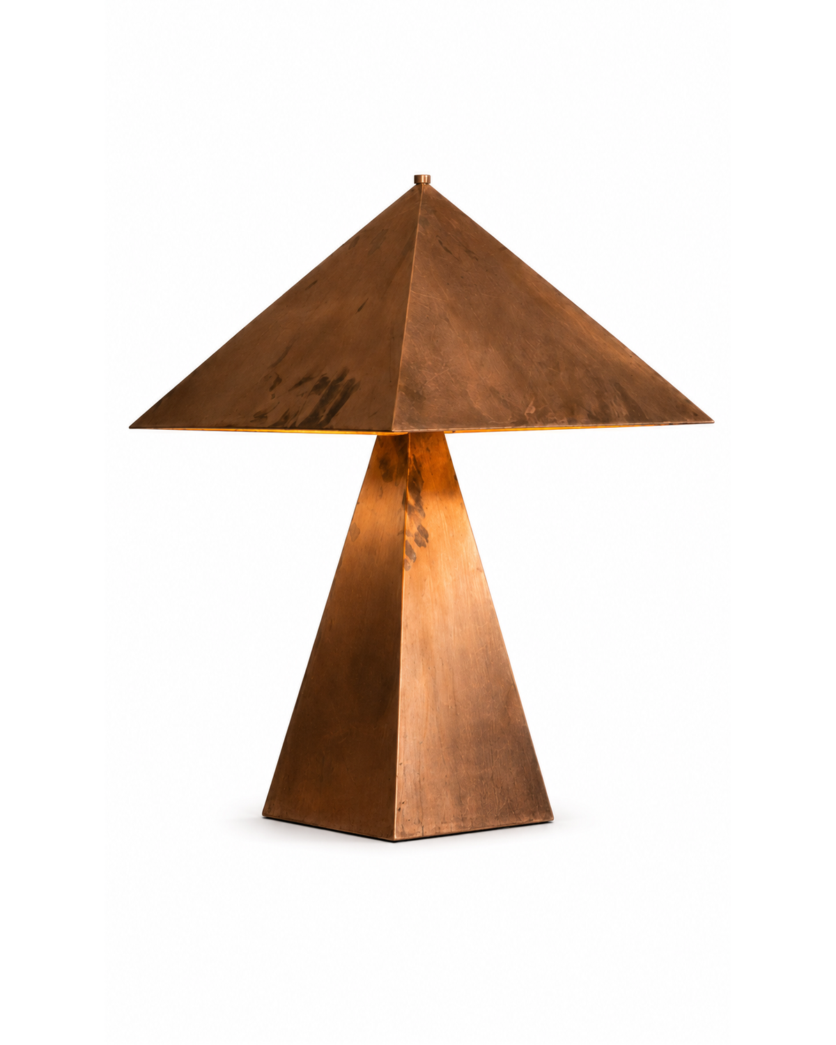 The Oriental Table Lamp by The Qratist features a handcrafted solid copper pyramidal shade and tapered geometric base, creating a timeless sculptural table lamp with warm ambient illumination.