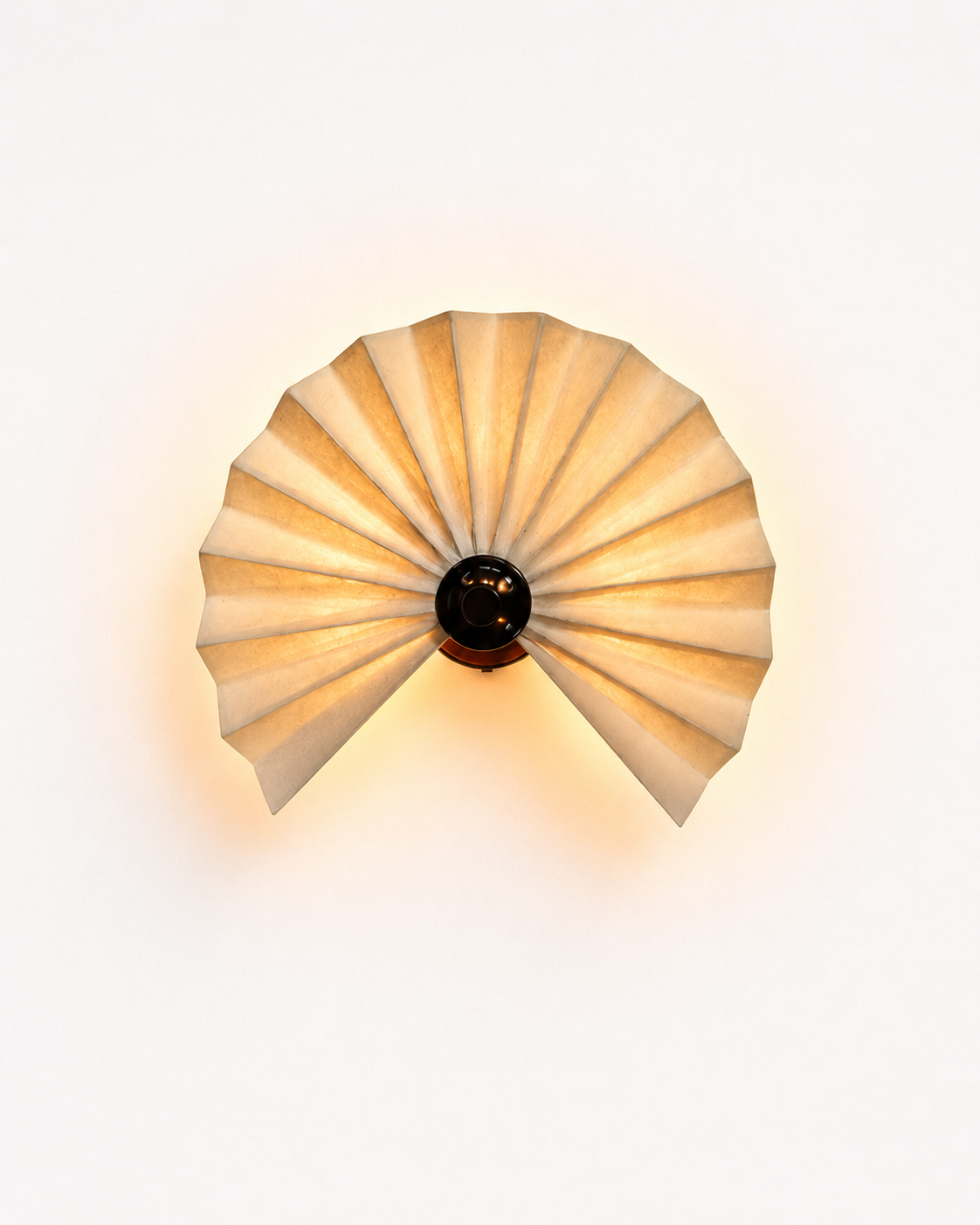 The Sensu Wall Light by The Qratist features handcrafted folded paper panels and a metal frame inspired by the traditional Japanese sensu fan, creating warm ambient illumination.