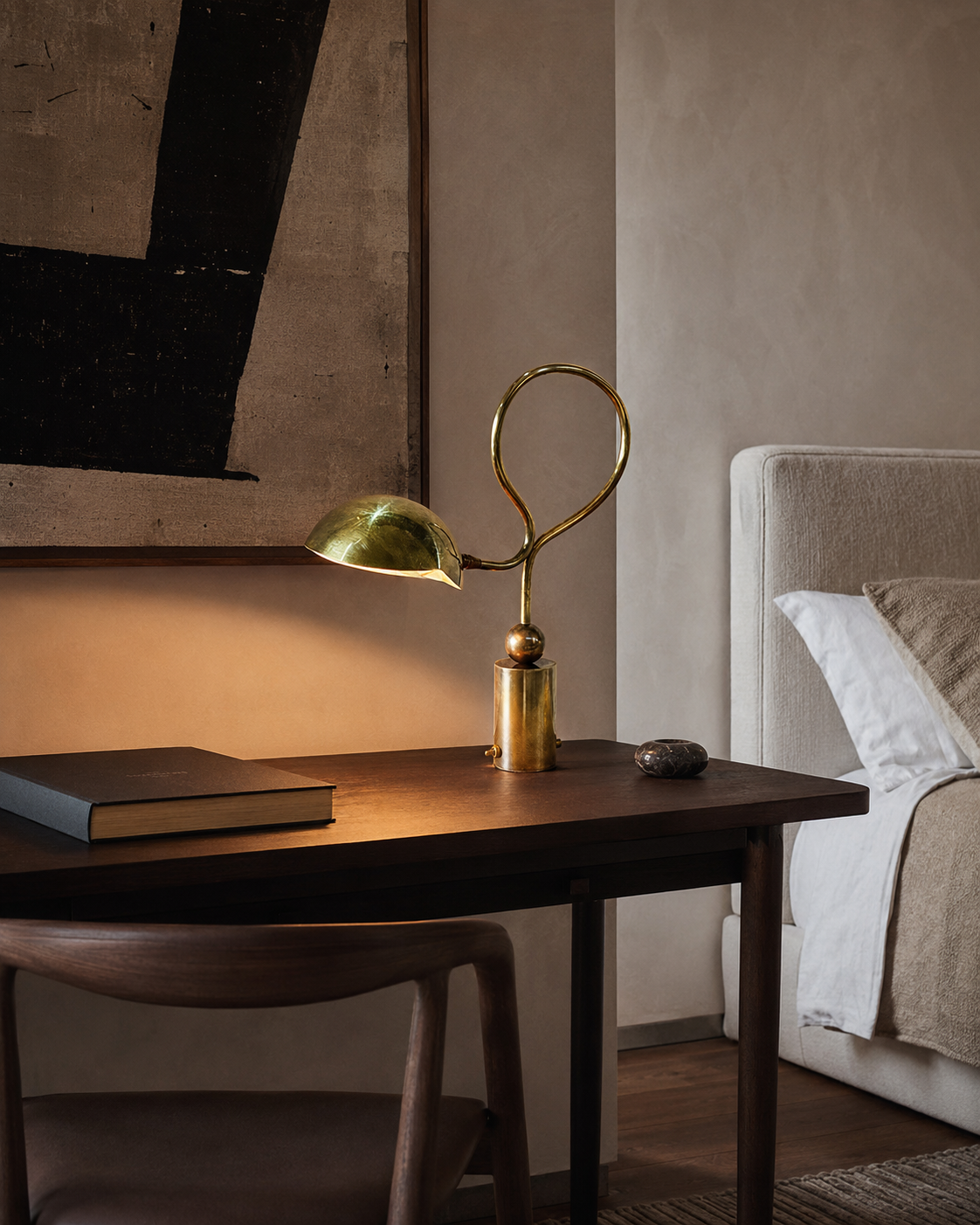 The Serpenti Table Lamp by The Qratist features a handcrafted solid brass looping frame with an adjustable dome shade, creating a sculptural table lamp with elegant warm ambient illumination.