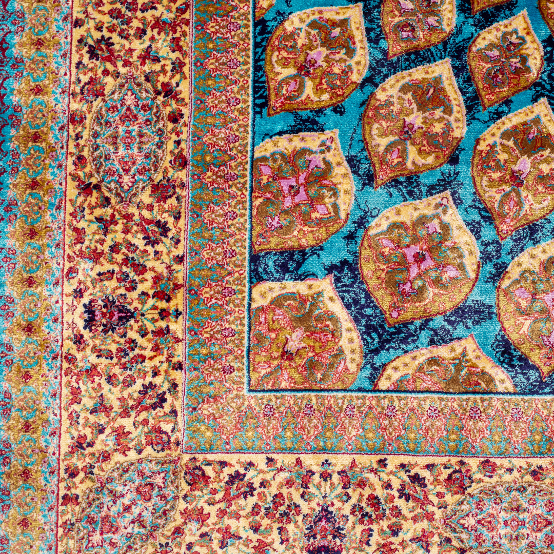 Verta silk rug featuring a turquoise blue base with intricate gold, ruby red, ivory, and fuchsia floral medallion design in a symmetrical pattern.