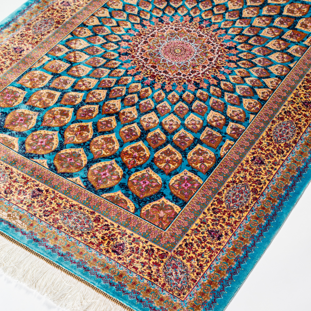 Verta silk rug featuring a turquoise blue base with intricate gold, ruby red, ivory, and fuchsia floral medallion design in a symmetrical pattern.