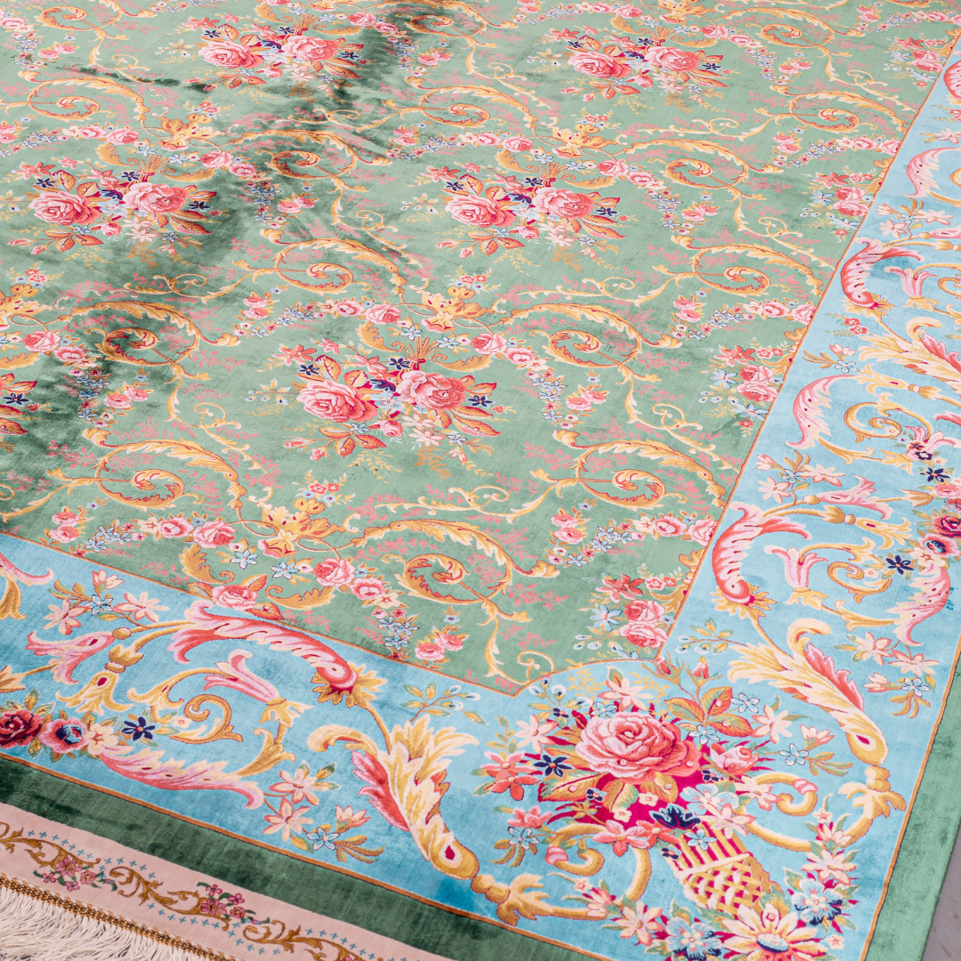 Green silk rug with detailed rose motifs and a turquoise border, featuring Persian-inspired floral designs and ornamental flourishes.