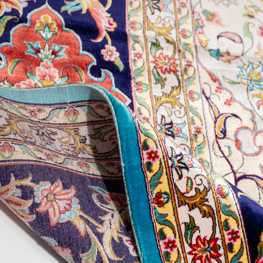 Intricately designed silk rug with turquoise base, floral patterns, and central medallion in red and gold – hand-finished and richly detailed.