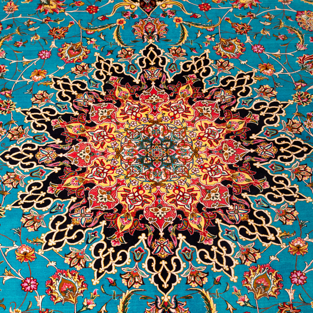 Intricately designed silk rug with turquoise base, floral patterns, and central medallion in red and gold – hand-finished and richly detailed.