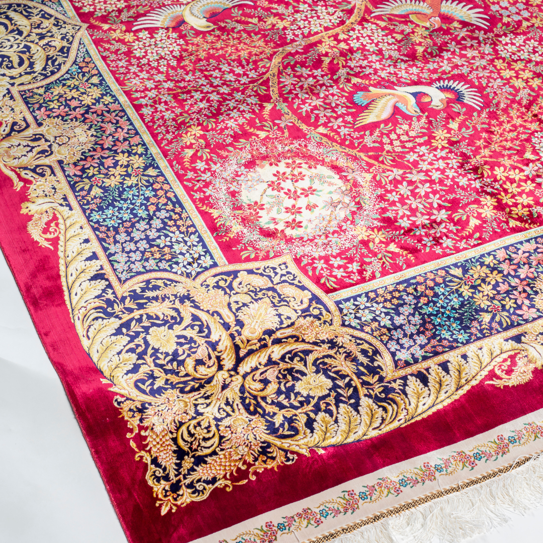 Silk rug with tree of life and bird motif, burgundy floral base, and ornate navy-gold borders. Handwoven with artistic precision.