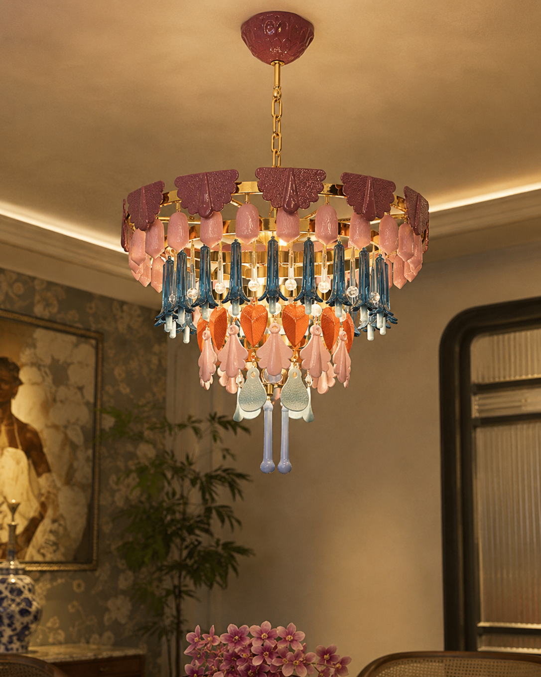 The Canopy Chandelier by The Qratist features handcrafted porcelain petals and coloured glass accents suspended from a gold plated frame, creating a layered botanical statement inspired by a flourishing garden canopy.