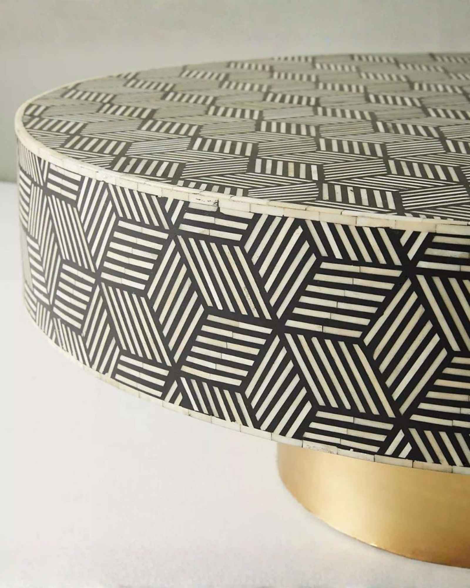 Round black bone inlay coffee table with a bold geometric pattern and gold base. A modern centerpiece for elegant living spaces.