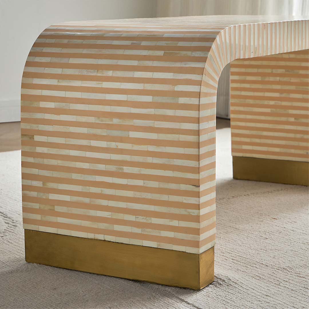 Modern beige bone inlay coffee table with curved edges and gold base. Features a striped inlay design for an elegant aesthetic.