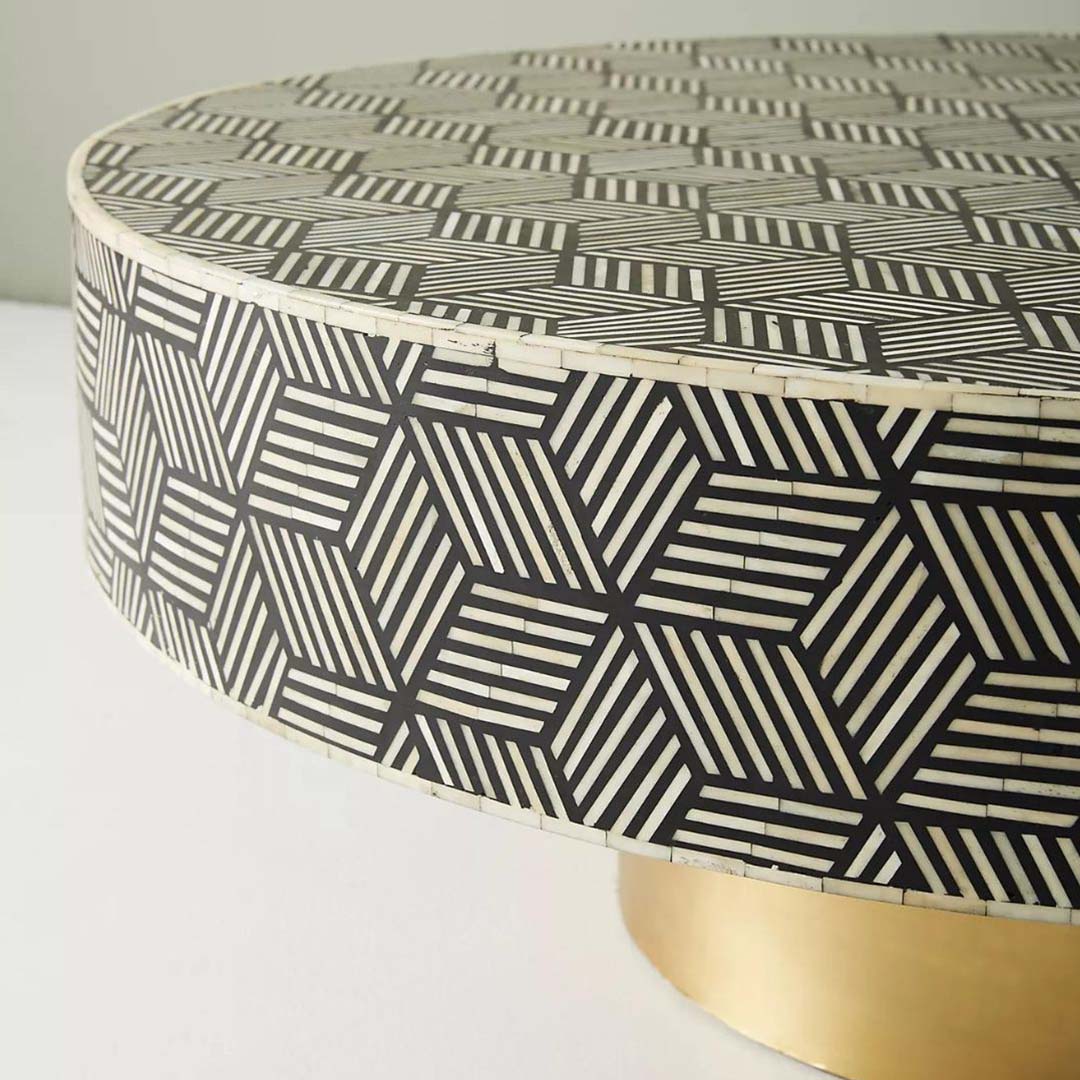 Round black bone inlay coffee table with a bold geometric pattern and gold base. A modern centerpiece for elegant living spaces.