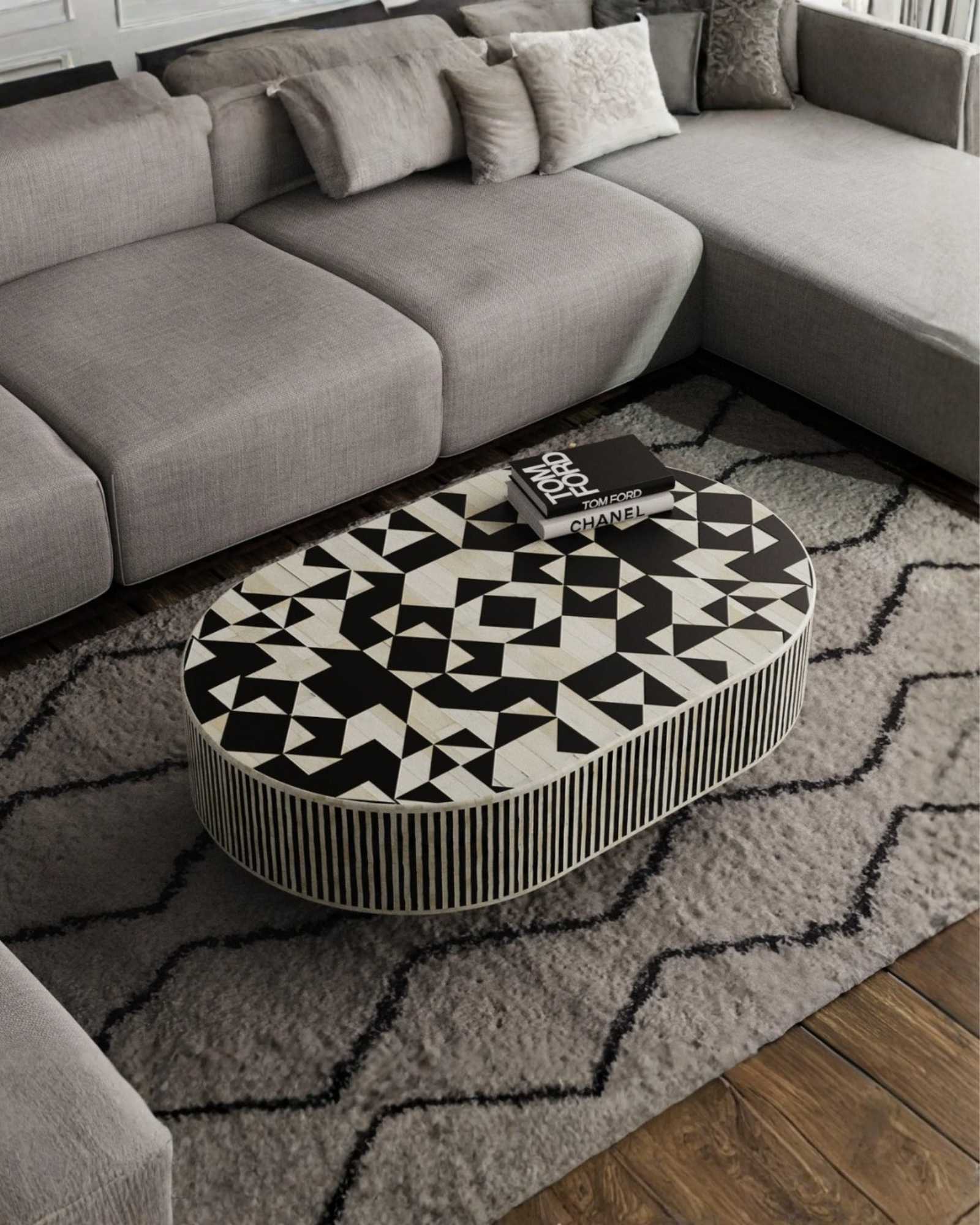 Black and white bone inlay coffee table with geometric pattern and gold base in contemporary setting.