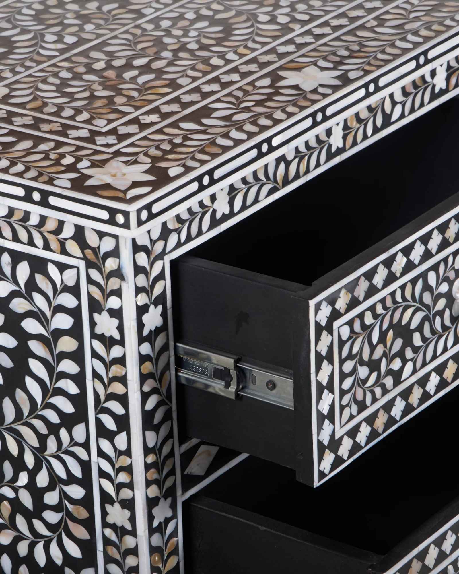A handcrafted black mother of pearl inlay chest of drawers, featuring intricate floral patterns and geometric designs, with crystal knobs and smooth drawer slides.