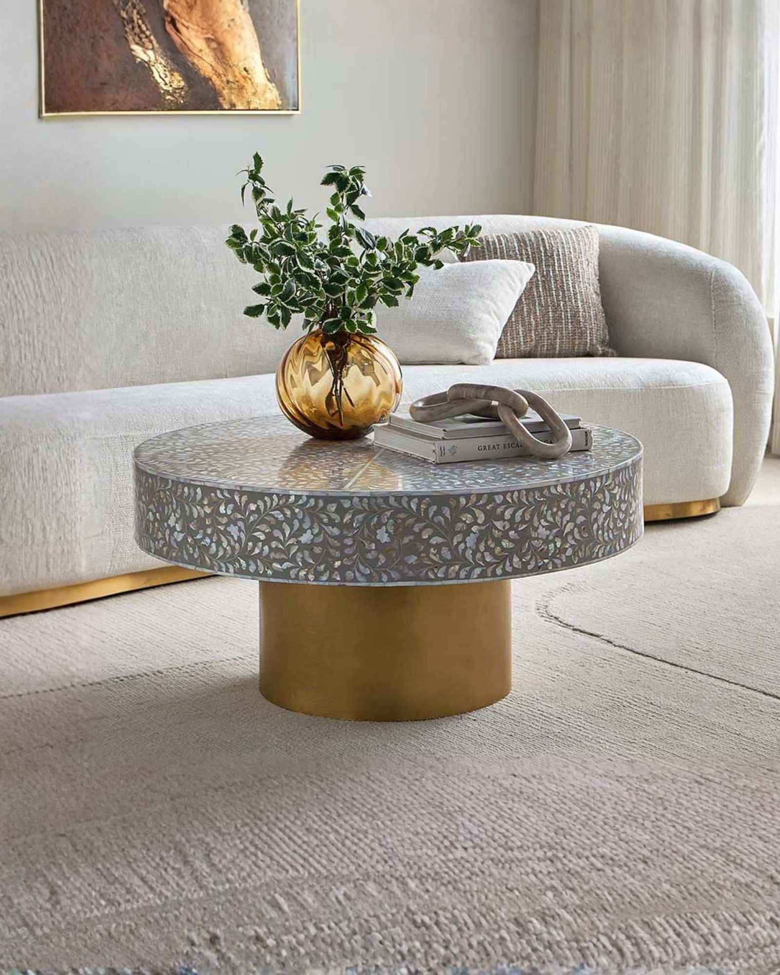 Round grey mother of pearl inlay coffee table with intricate floral design and a gold cylindrical metallic base.