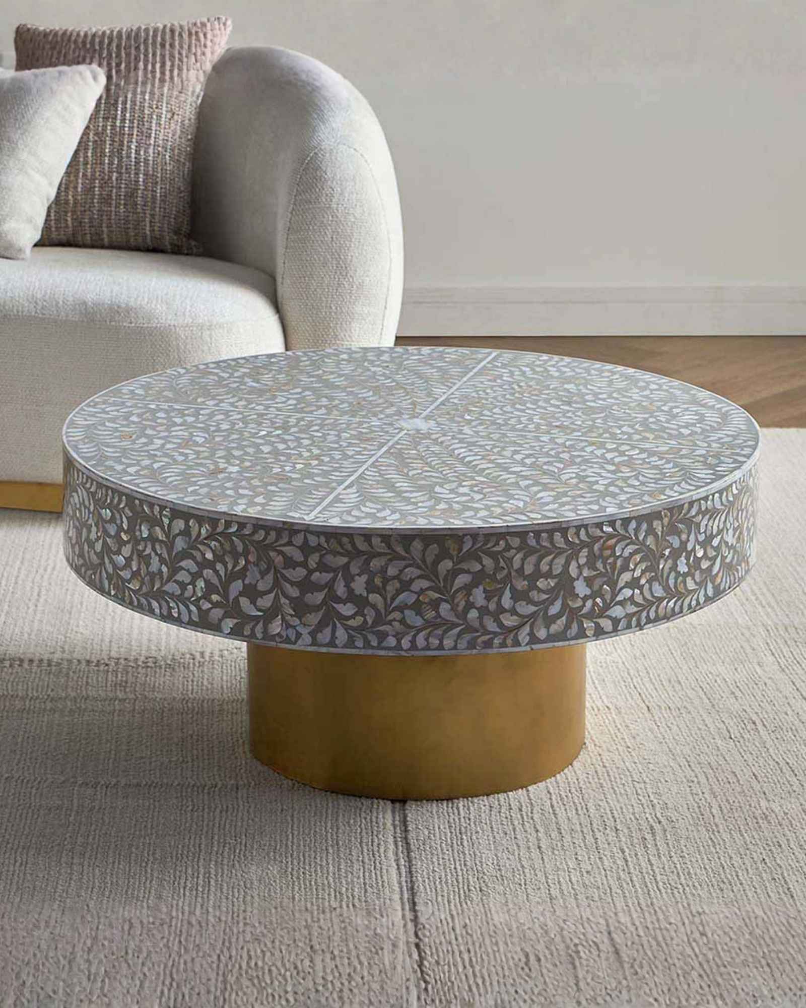 Round grey mother of pearl inlay coffee table with intricate floral design and a gold cylindrical metallic base.