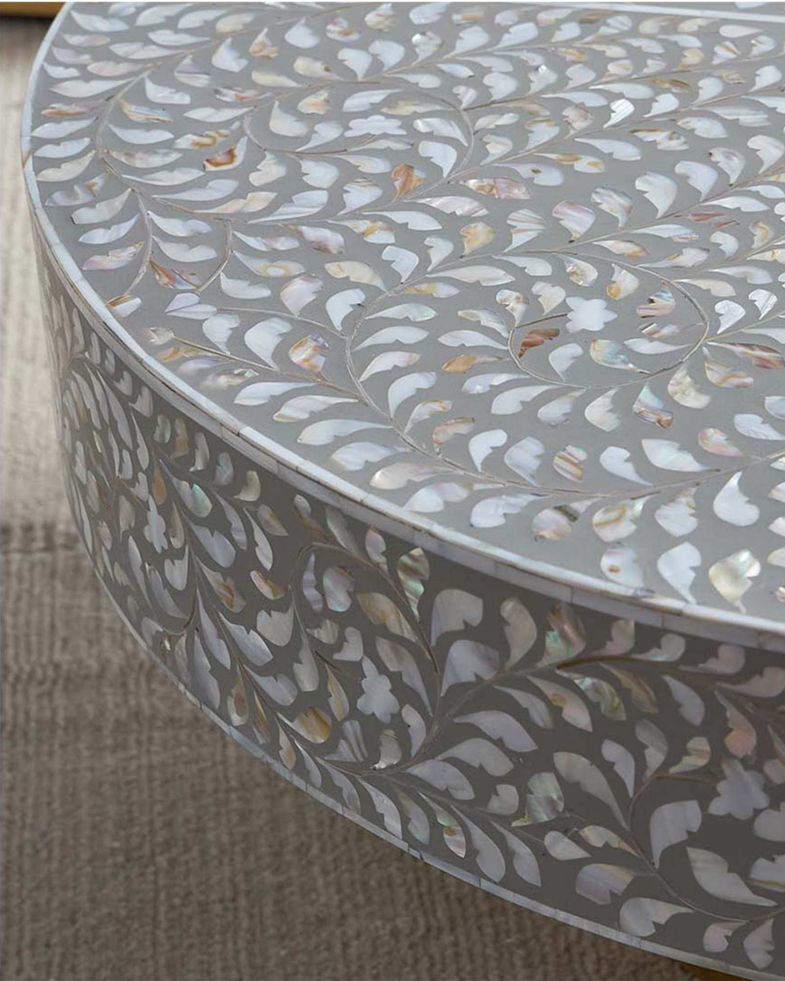 Round grey mother of pearl inlay coffee table with intricate floral design and a gold cylindrical metallic base.