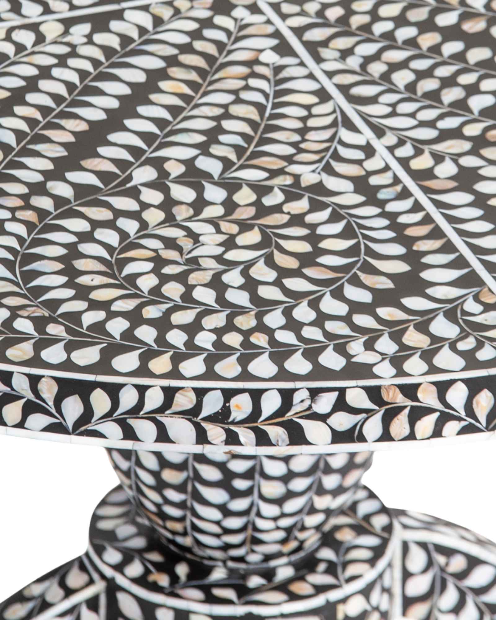 Handcrafted Iris dining table featuring black mother of pearl inlay with a round top and sculptural pedestal base.