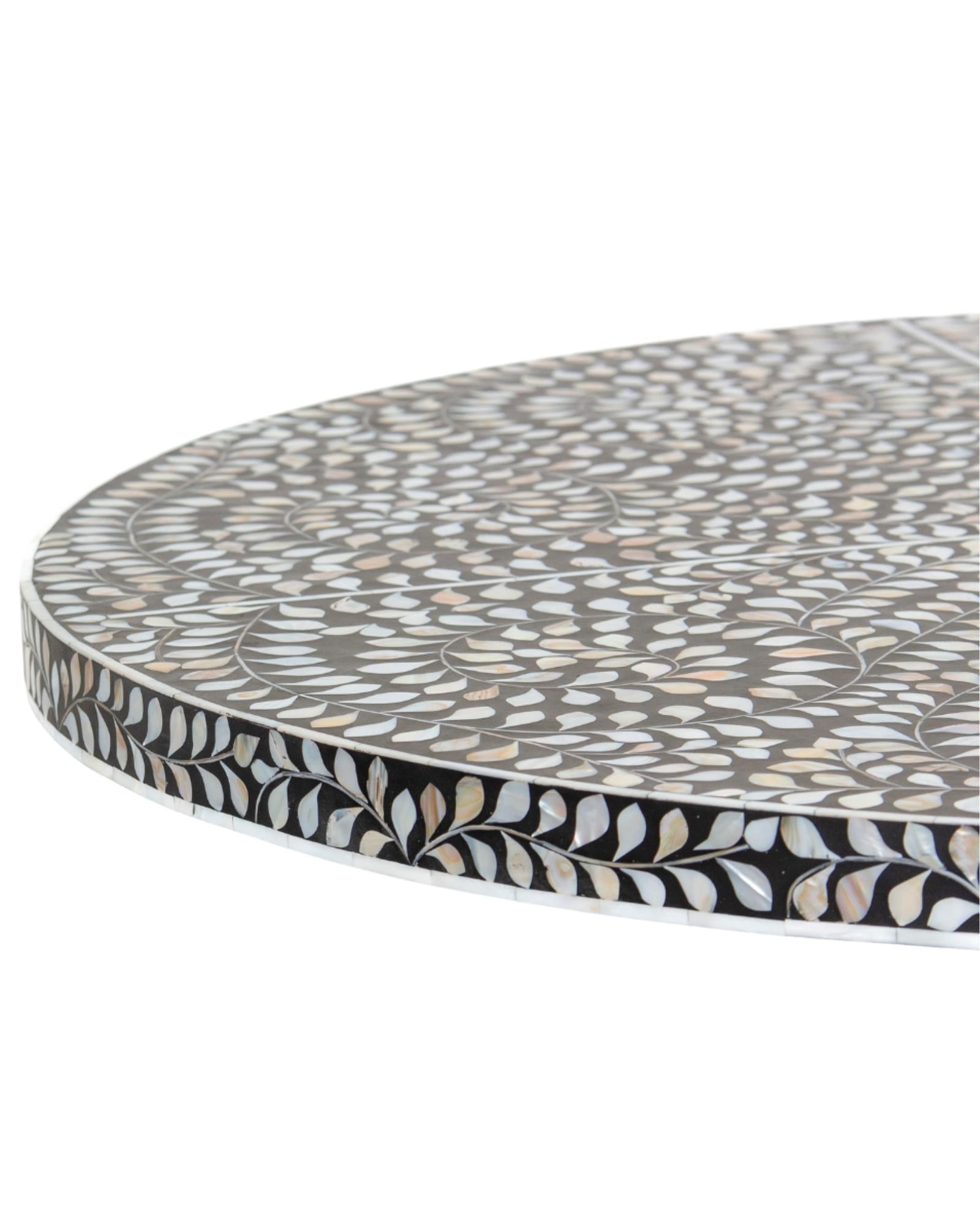 Handcrafted Iris dining table featuring black mother of pearl inlay with a round top and sculptural pedestal base.
