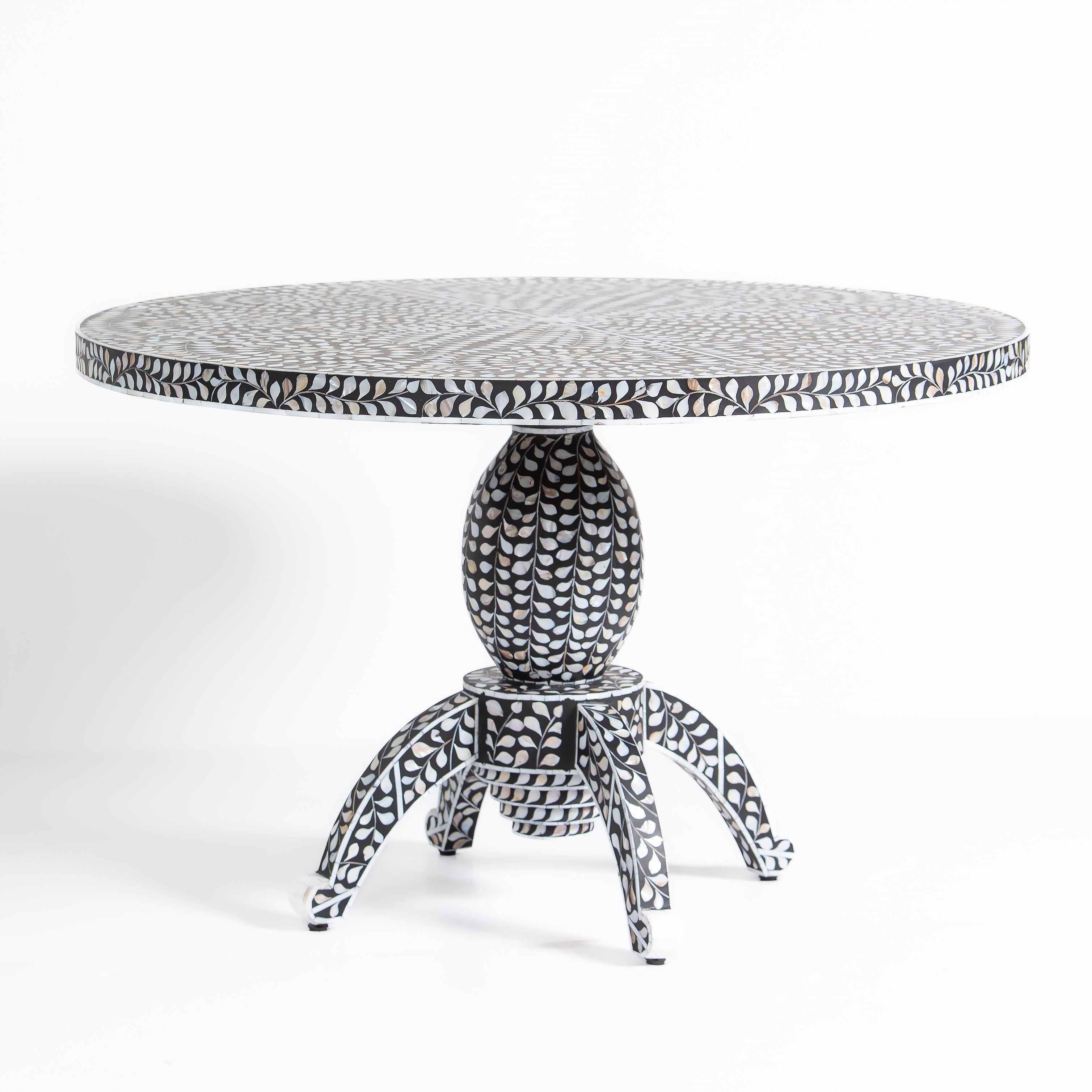 Handcrafted Iris dining table featuring black mother of pearl inlay with a round top and sculptural pedestal base.