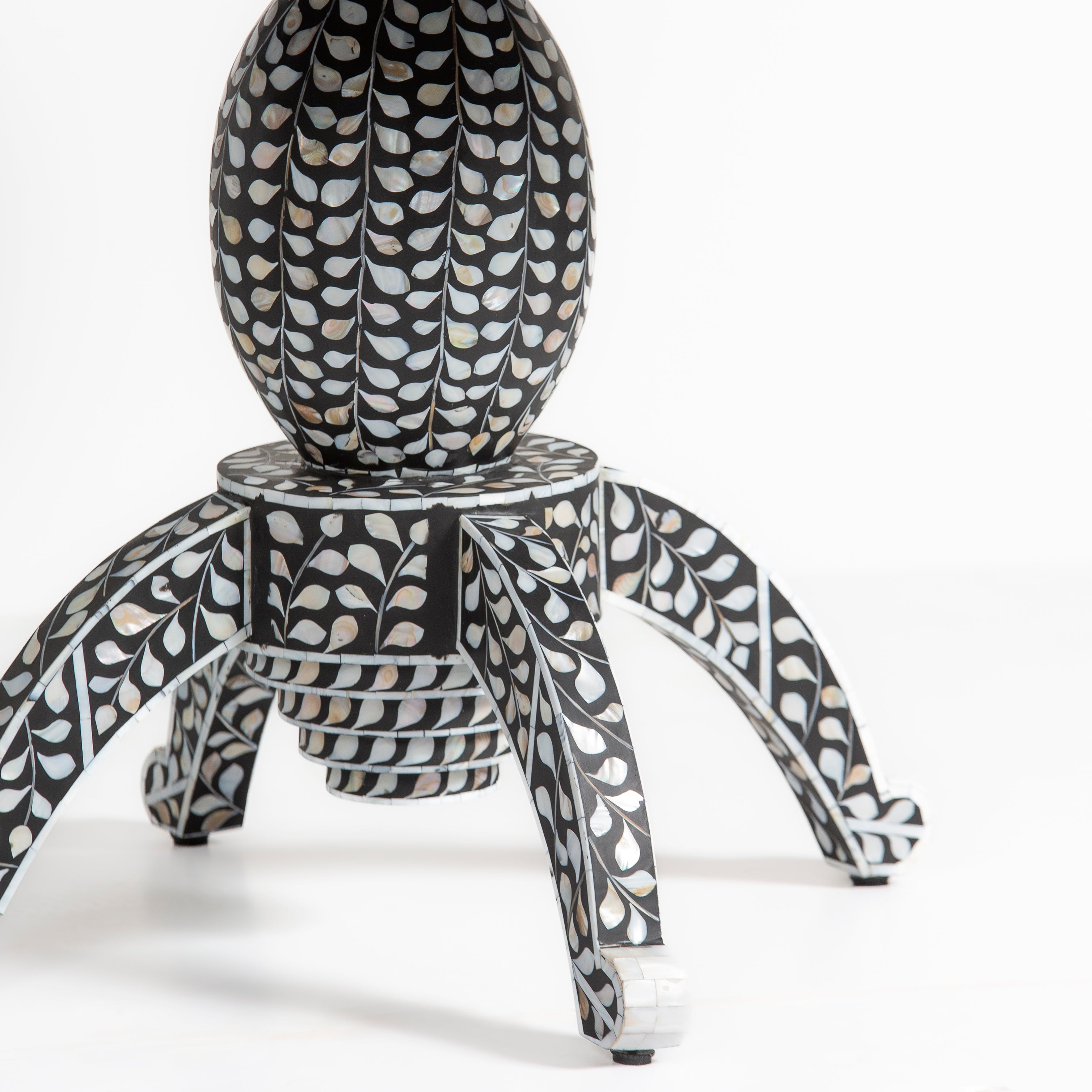 Handcrafted Iris dining table featuring black mother of pearl inlay with a round top and sculptural pedestal base.