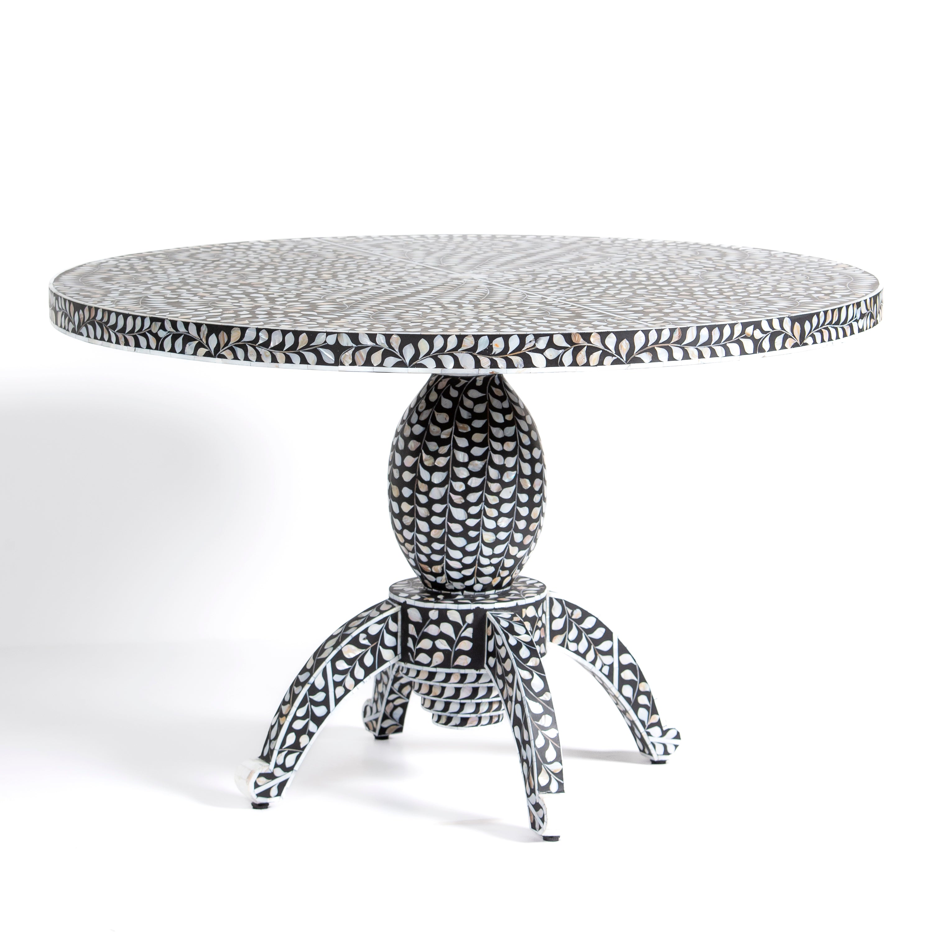 Handcrafted Iris dining table featuring black mother of pearl inlay with a round top and sculptural pedestal base.