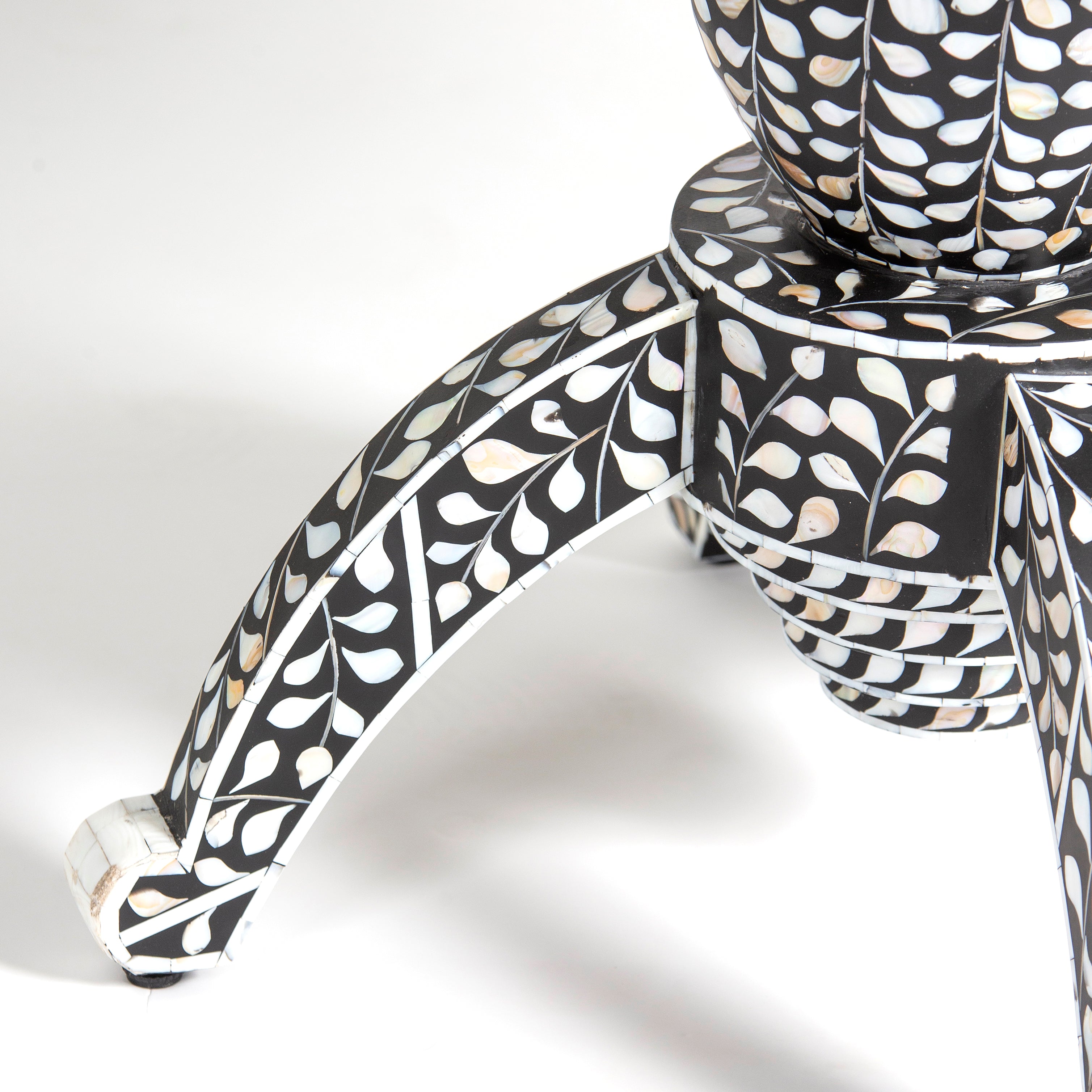 Handcrafted Iris dining table featuring black mother of pearl inlay with a round top and sculptural pedestal base.