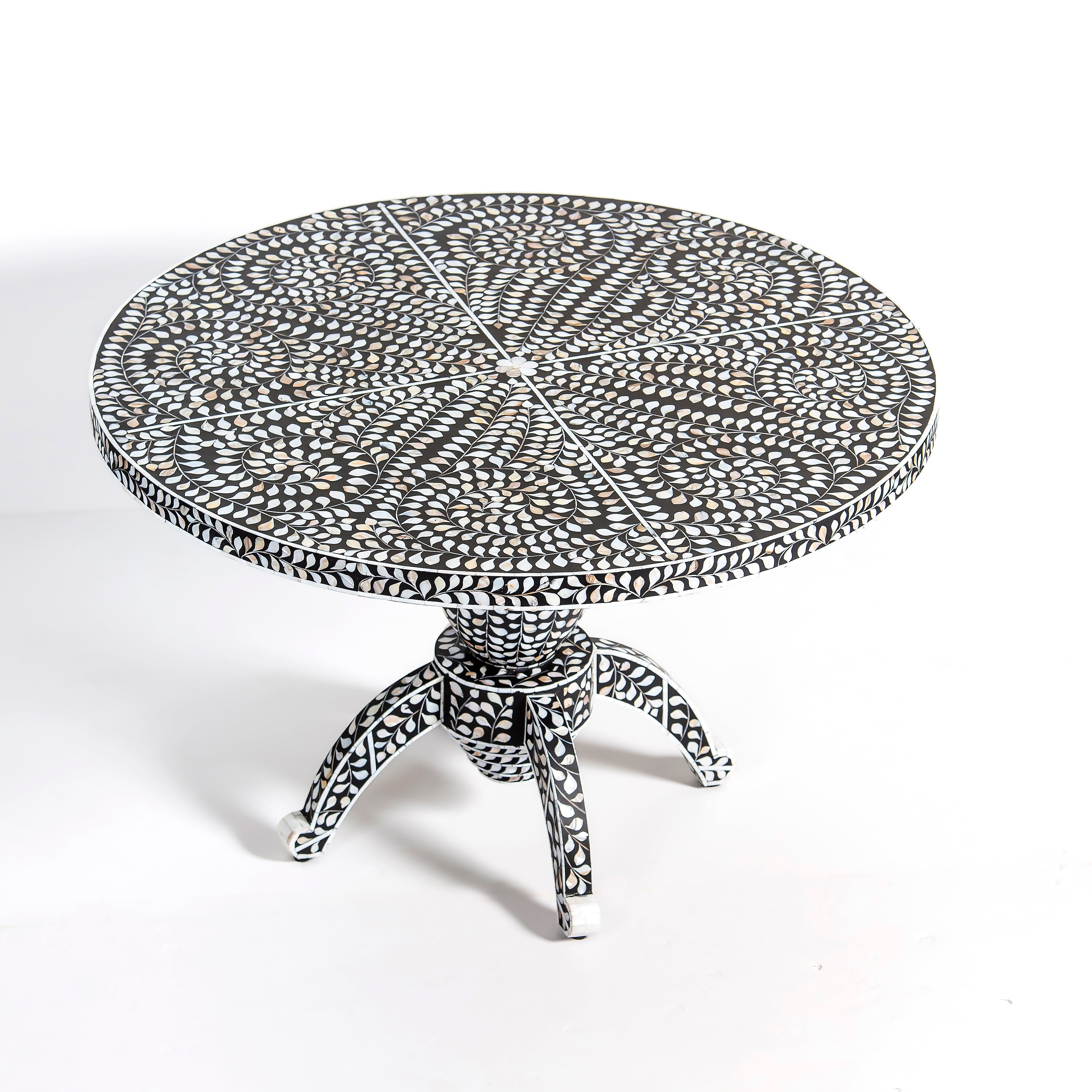 Handcrafted Iris dining table featuring black mother of pearl inlay with a round top and sculptural pedestal base.