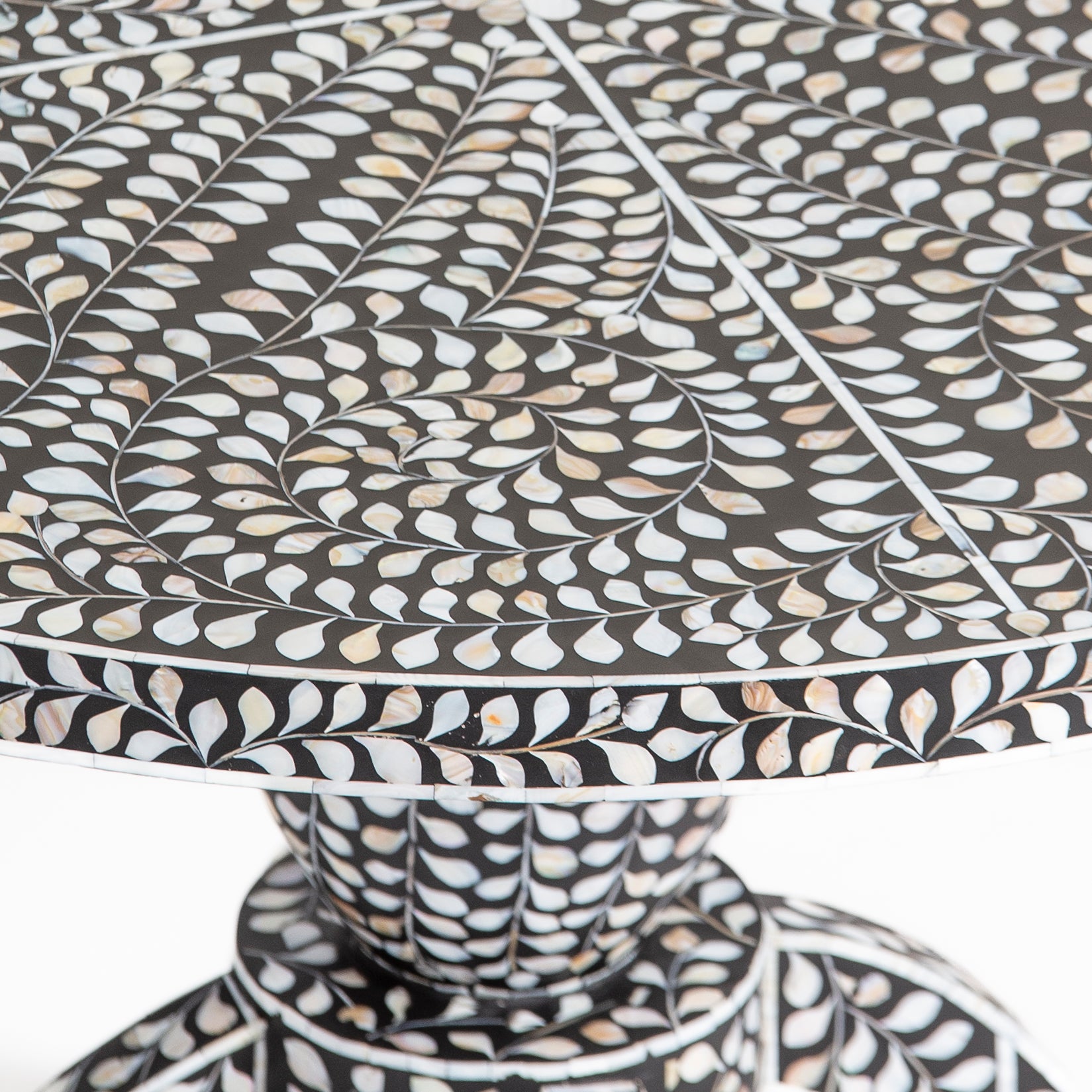 Handcrafted Iris dining table featuring black mother of pearl inlay with a round top and sculptural pedestal base.