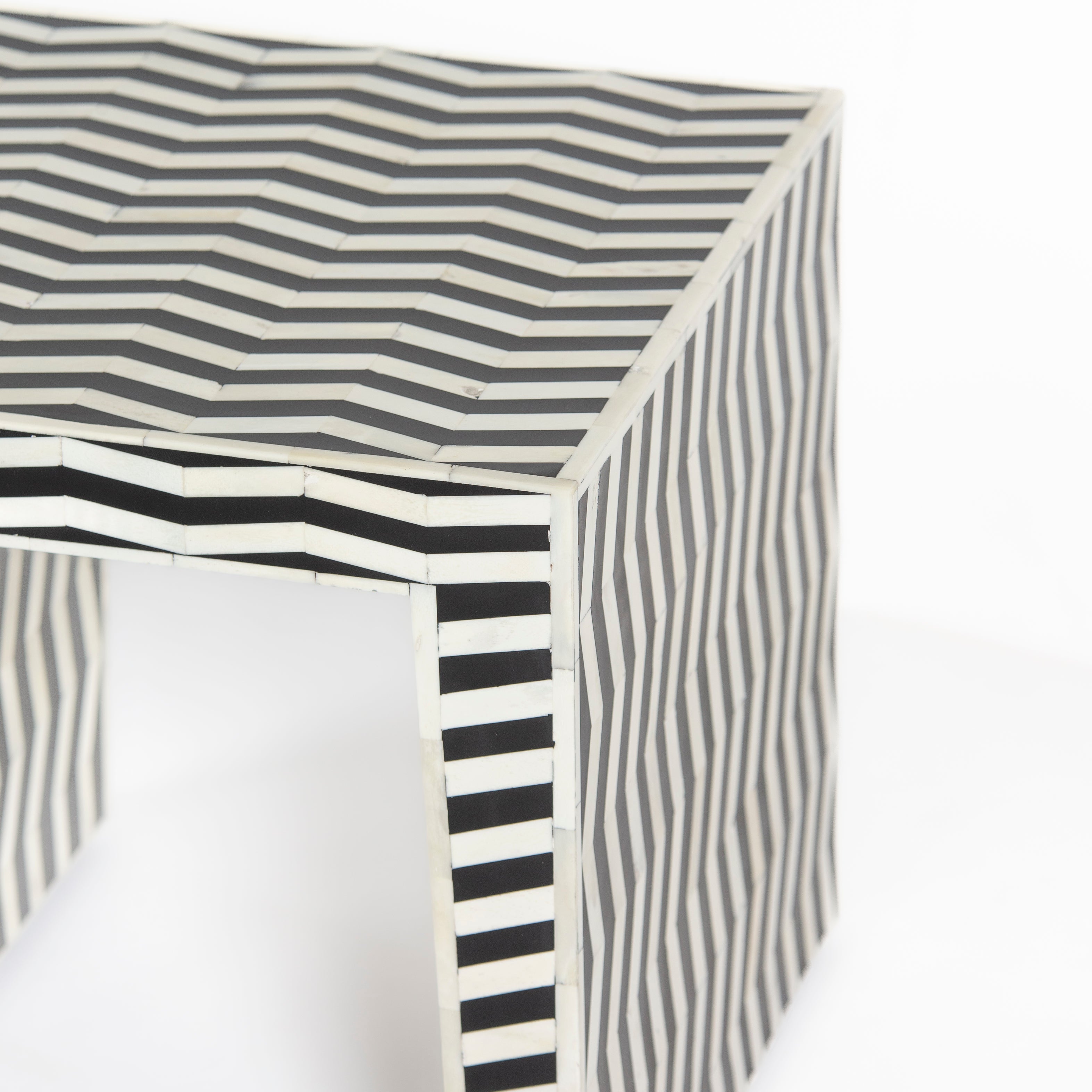 Handcrafted Isra side table featuring black bone inlay with geometric striped detailing and a compact cubic form.