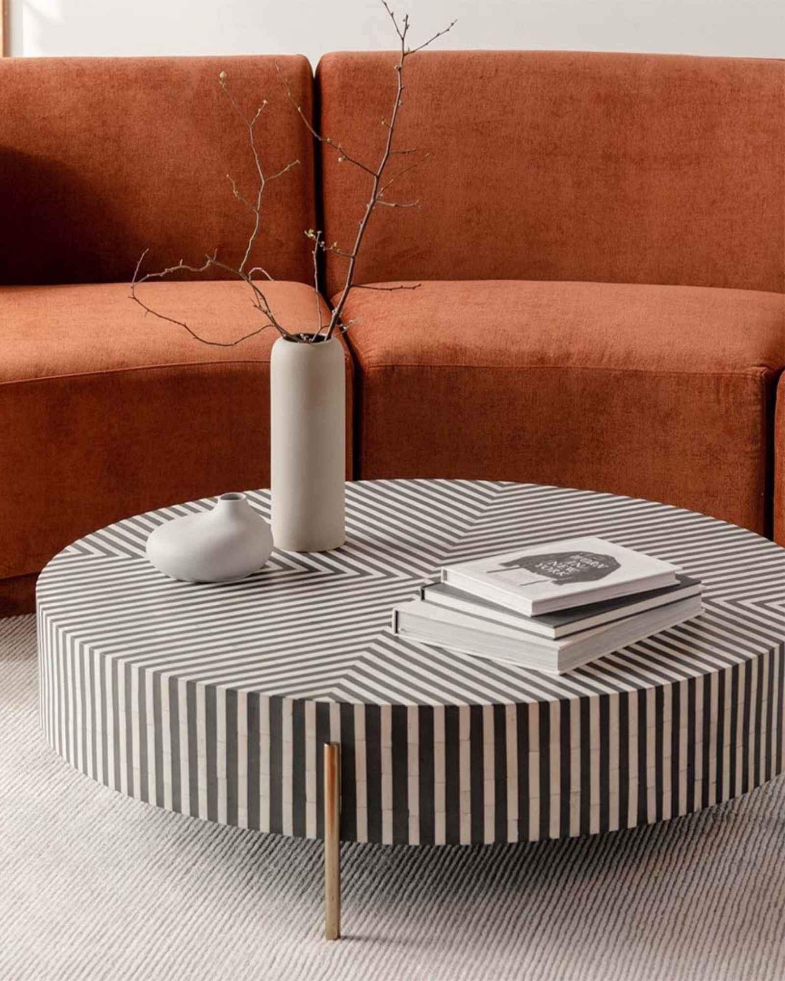 Round black bone inlay coffee table with striped design and brass legs.