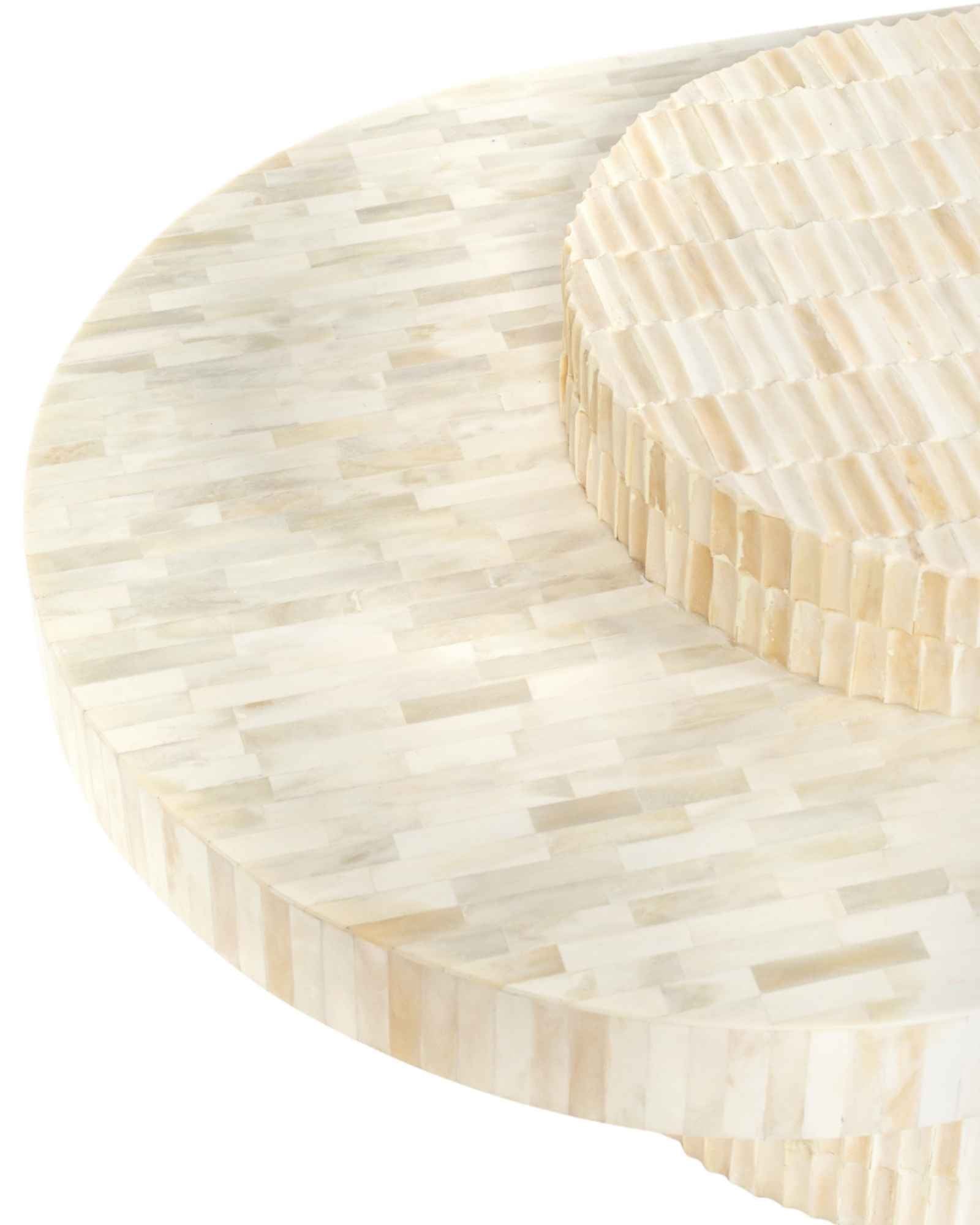 Sculptural bone carved coffee table with layered design in soft neutral tones, handcrafted with curved tiers and textured artisanal detailing.
