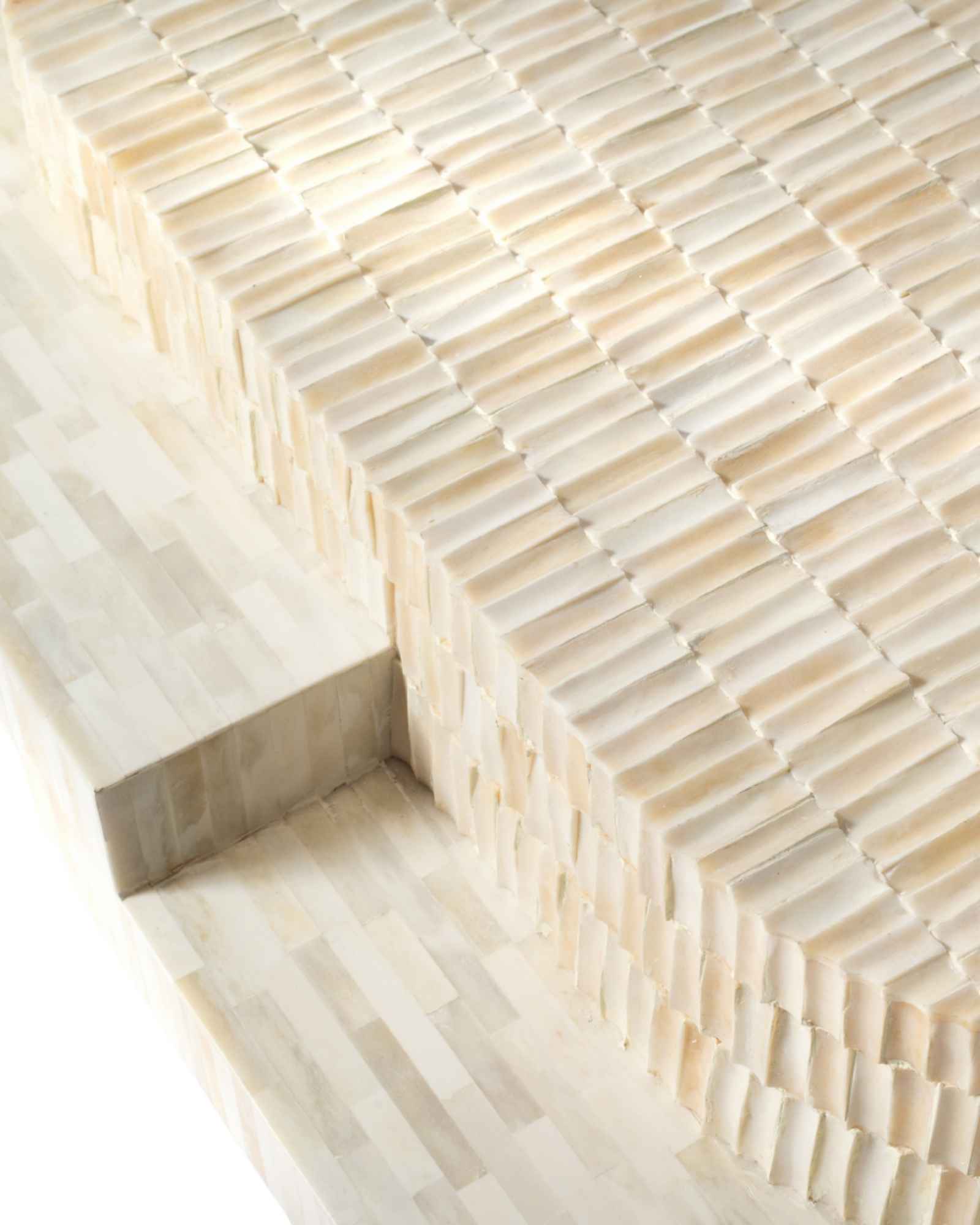 Sculptural bone carved coffee table with layered design in soft neutral tones, handcrafted with curved tiers and textured artisanal detailing.