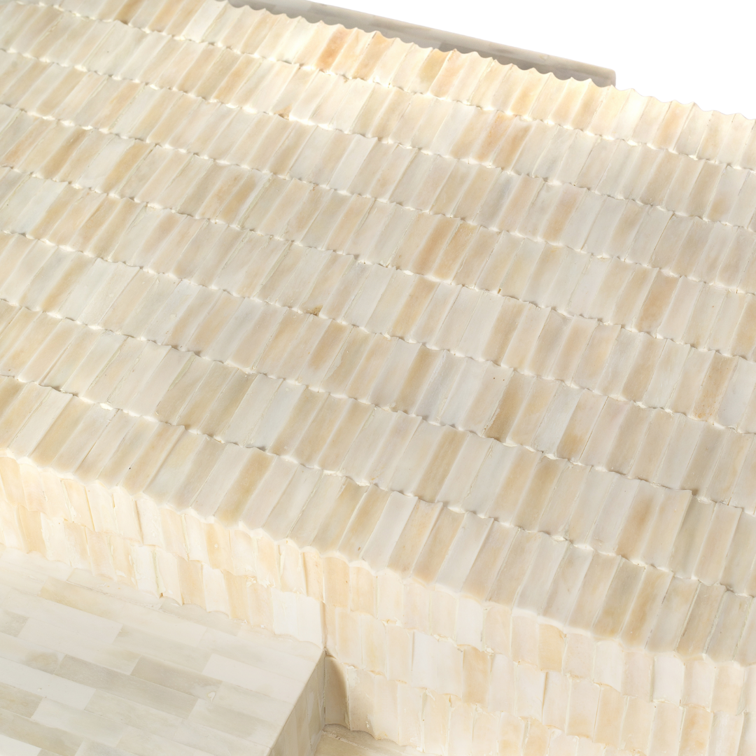 Sculptural bone carved coffee table with layered design in soft neutral tones, handcrafted with curved tiers and textured artisanal detailing.