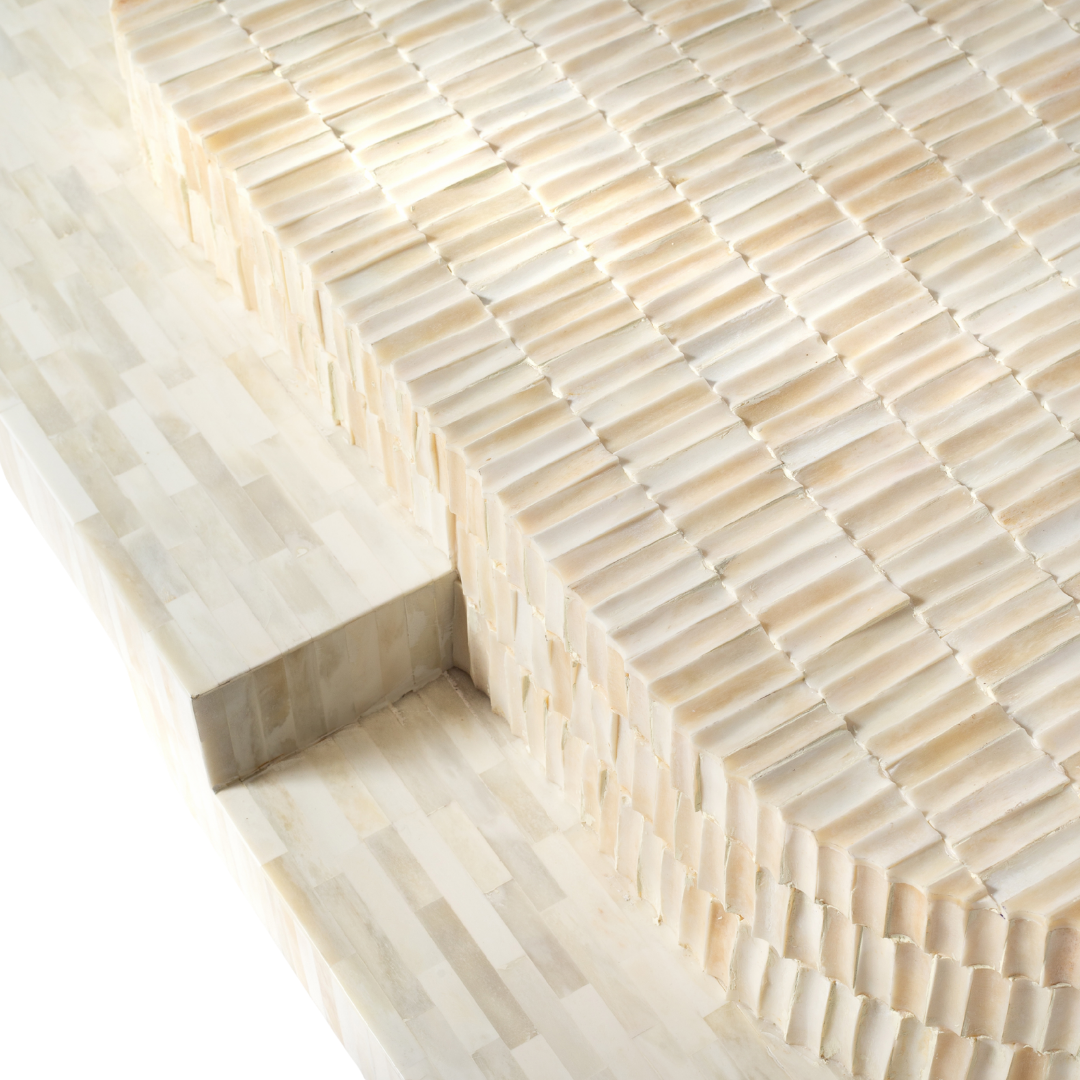 Sculptural bone carved coffee table with layered design in soft neutral tones, handcrafted with curved tiers and textured artisanal detailing.