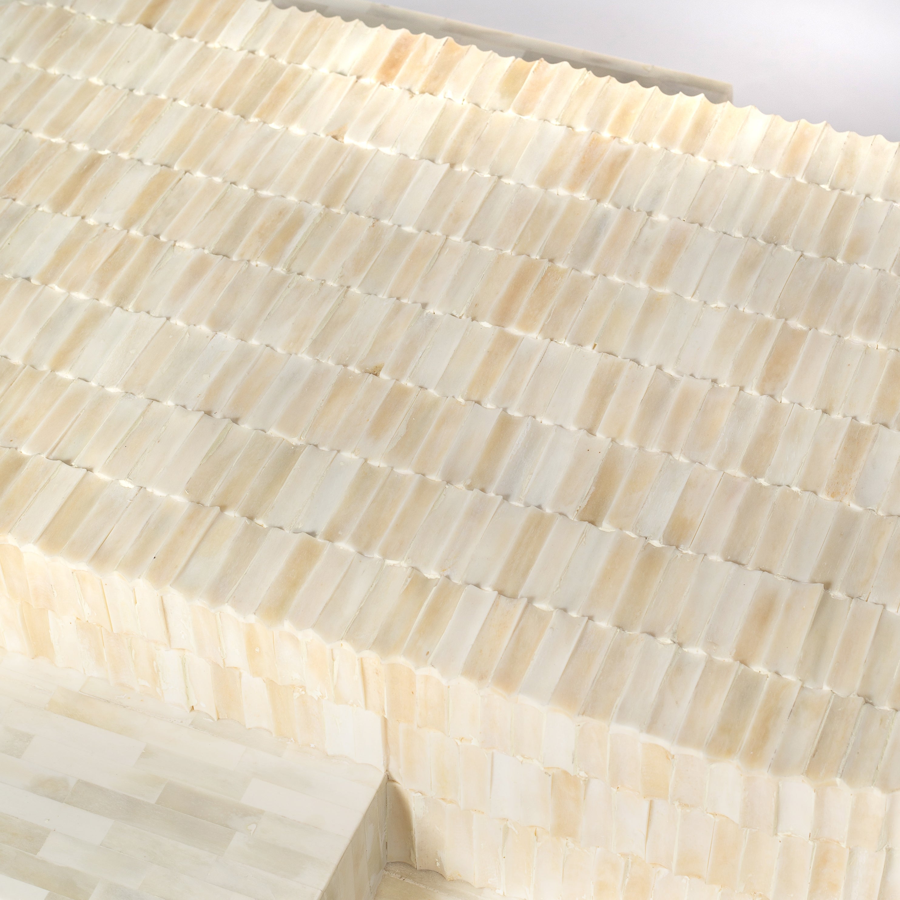 Sculptural bone carved coffee table with layered design in soft neutral tones, handcrafted with curved tiers and textured artisanal detailing.