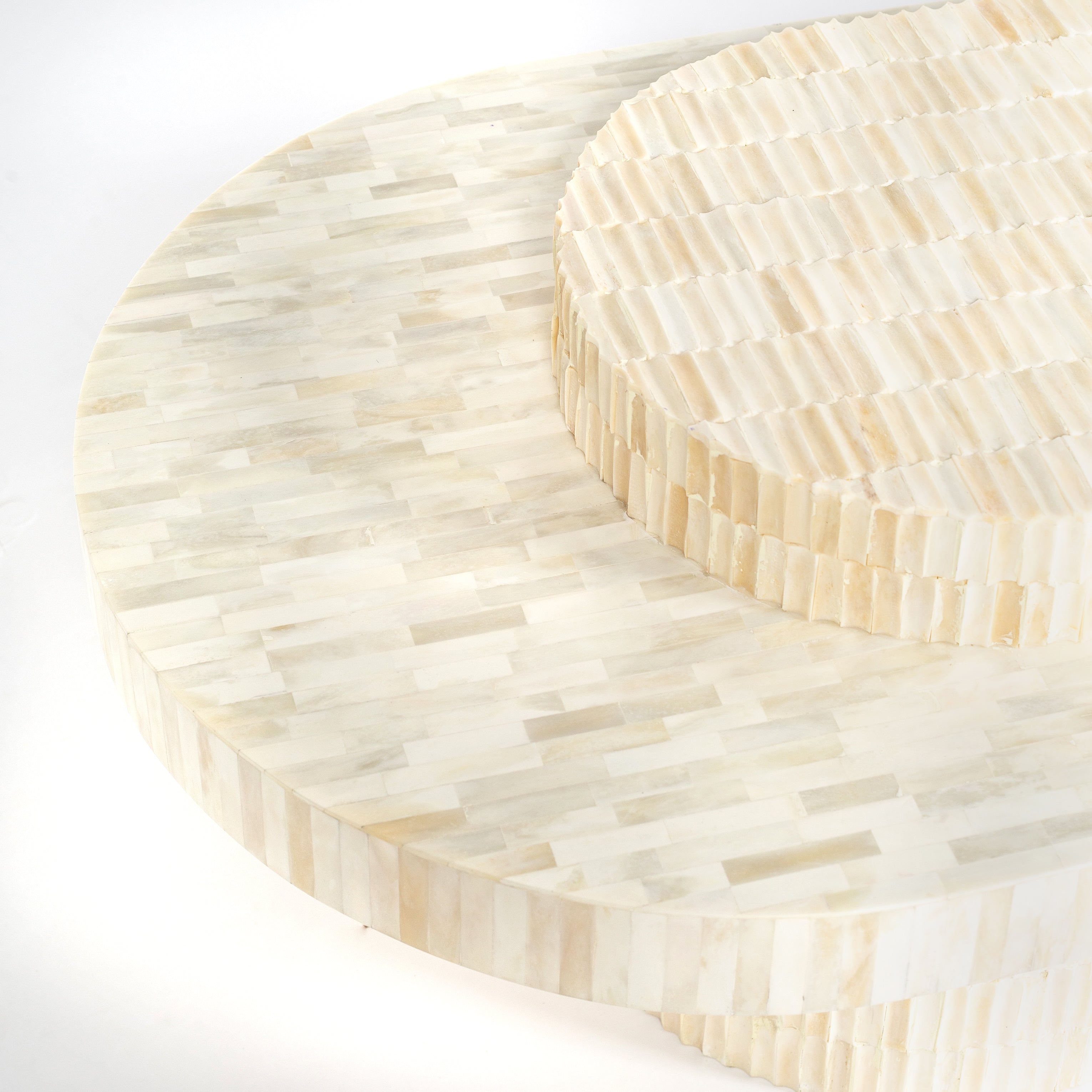 Sculptural bone carved coffee table with layered design in soft neutral tones, handcrafted with curved tiers and textured artisanal detailing.