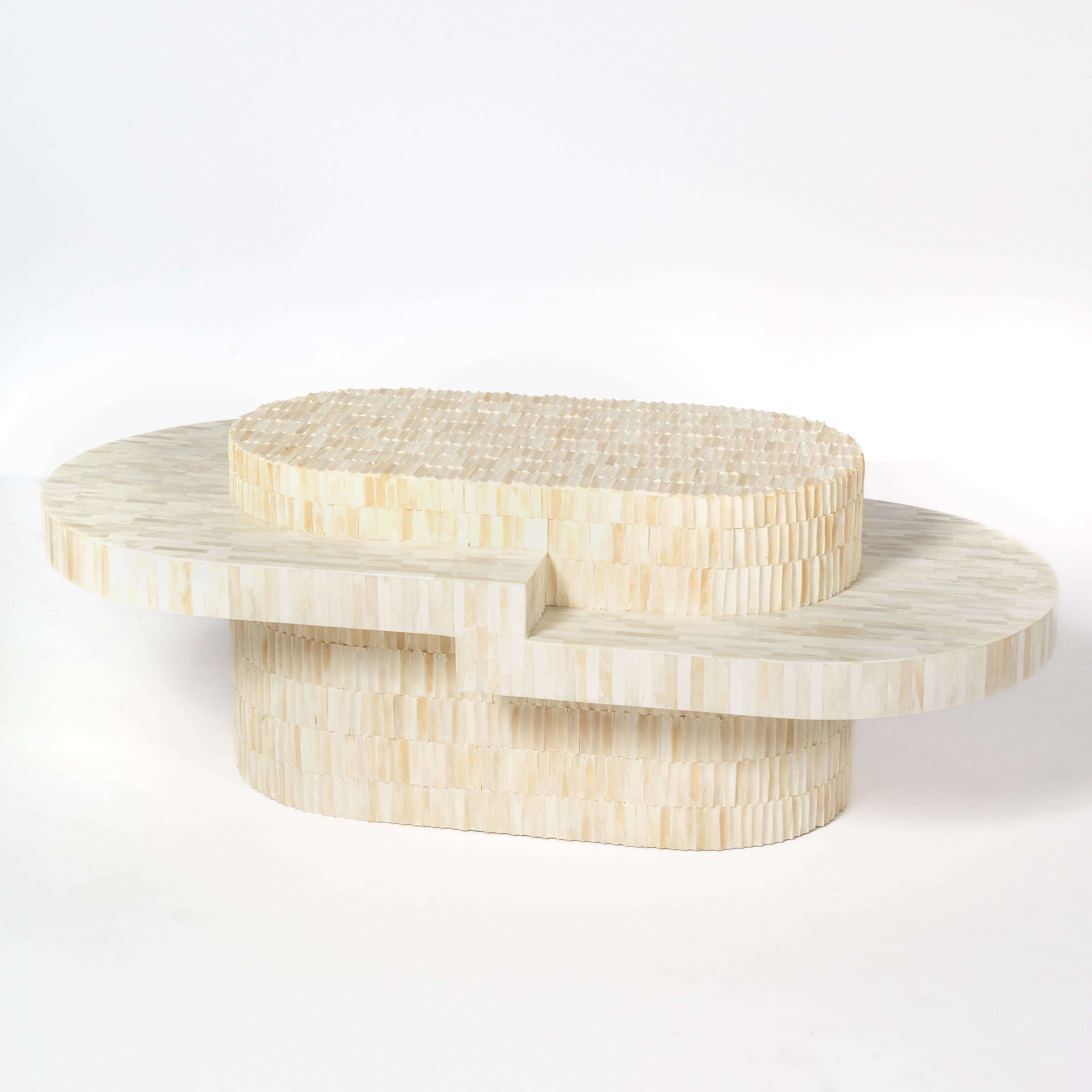 Sculptural bone carved coffee table with layered design in soft neutral tones, handcrafted with curved tiers and textured artisanal detailing.