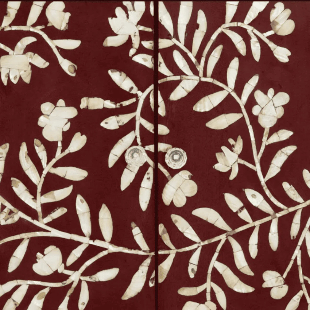 Handcrafted burgundy cabinet featuring intricate mother-of-pearl inlay, a floral pattern, and modern metal legs. A luxurious and functional storage piece.
