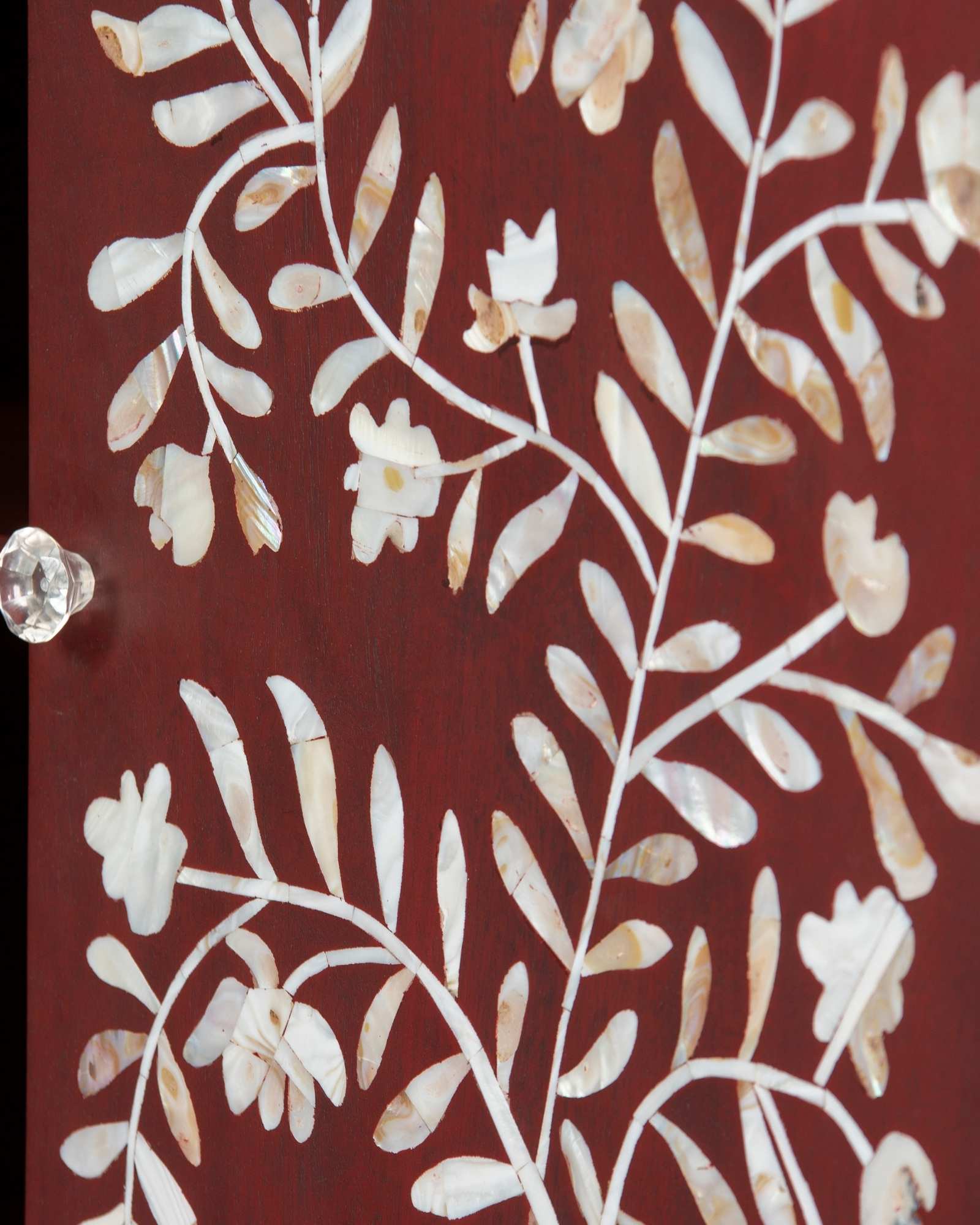 Mother of pearl inlay cabinet featuring intricate floral vine pattern in burgundy and white, handcrafted furniture piece.