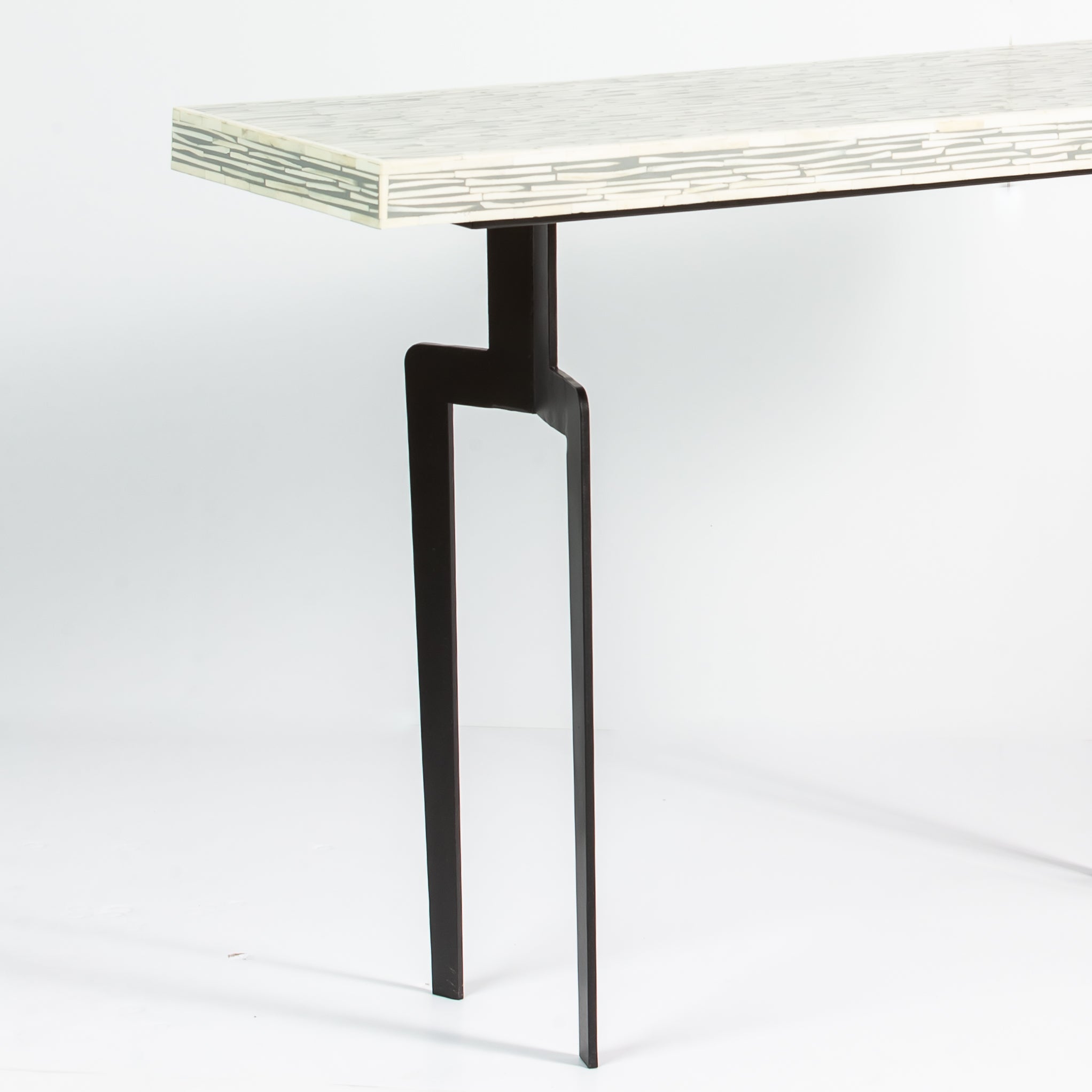 Minimalist table with a bone inlay top and black metal legs on a white background