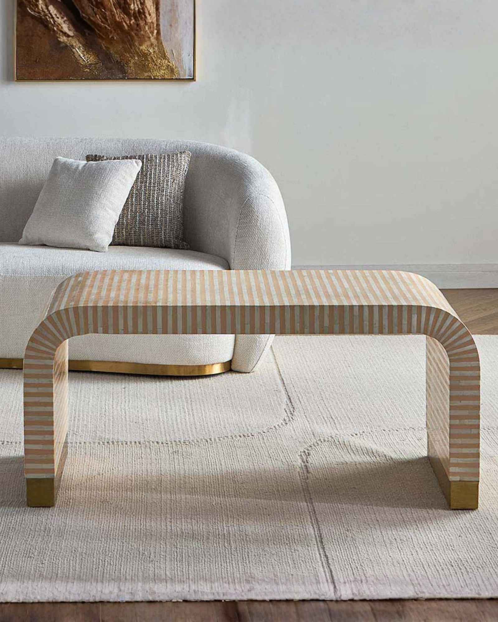 Modern beige bone inlay coffee table with curved edges and gold base. Features a striped inlay design for an elegant aesthetic.