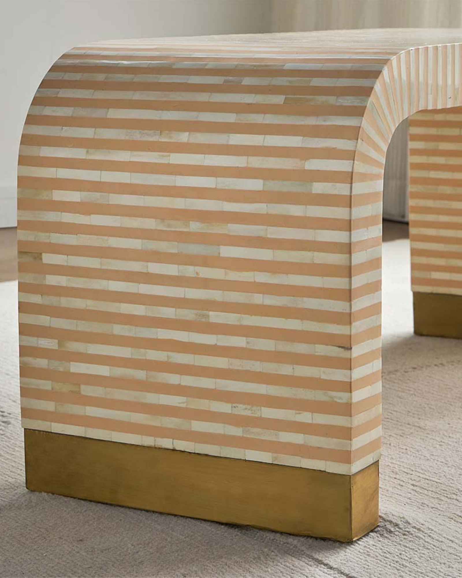 Modern beige bone inlay coffee table with curved edges and gold base. Features a striped inlay design for an elegant aesthetic.